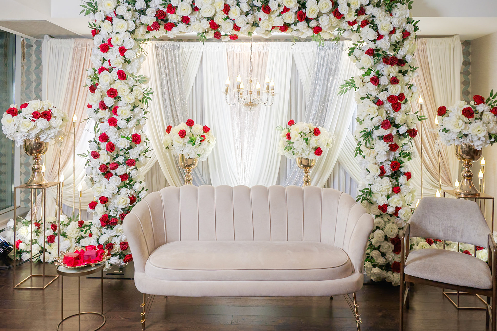 Elegant engagement stage decor with red and white roses and cream velvet loveseat, South Asian celebration in Toronto