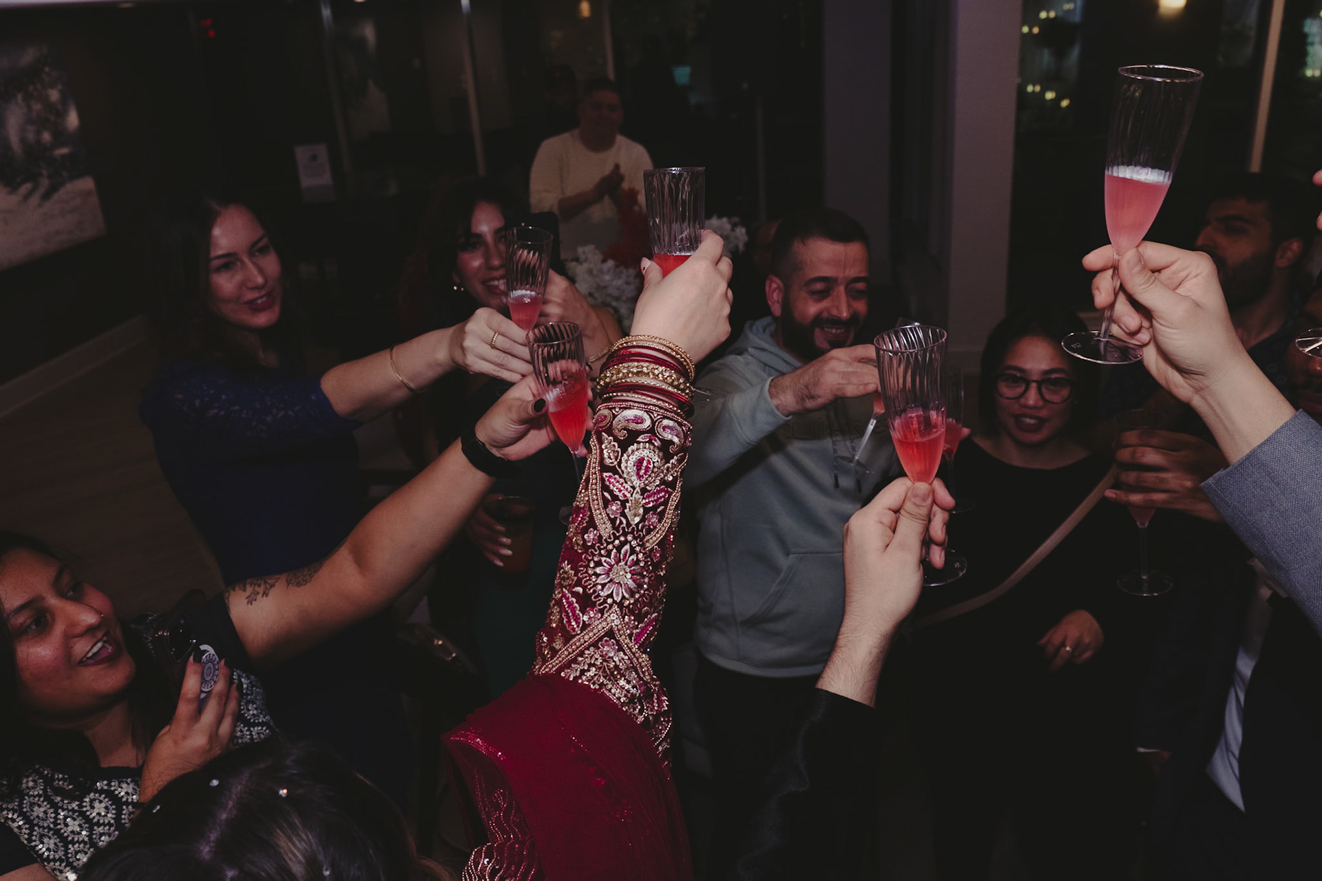 uests raising champagne glasses in celebration at South Asian engagement event in Toronto, candid party moment