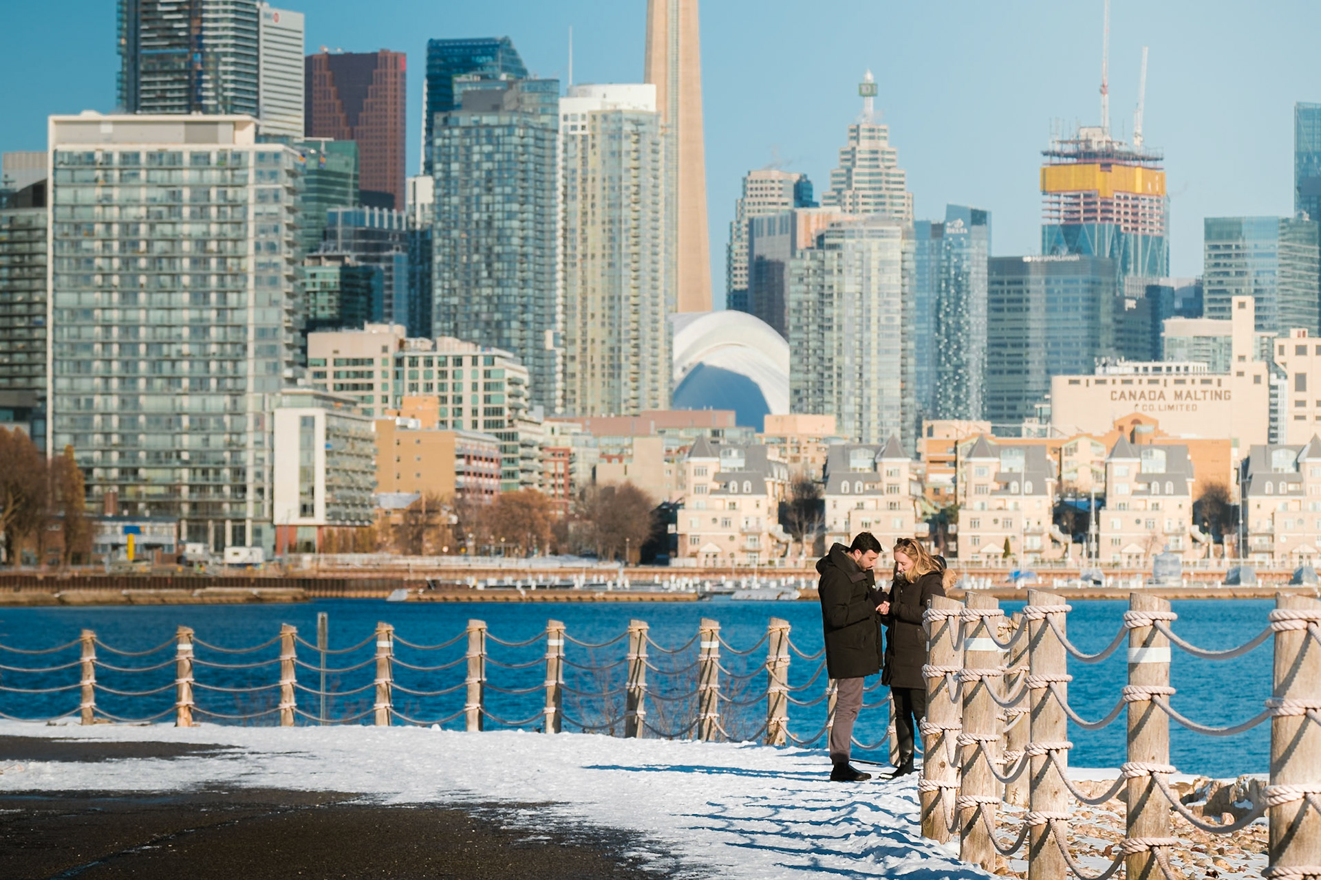 Romantic proposal moment along the icy lakeshore in Toronto with skyscraper skyline backdrop