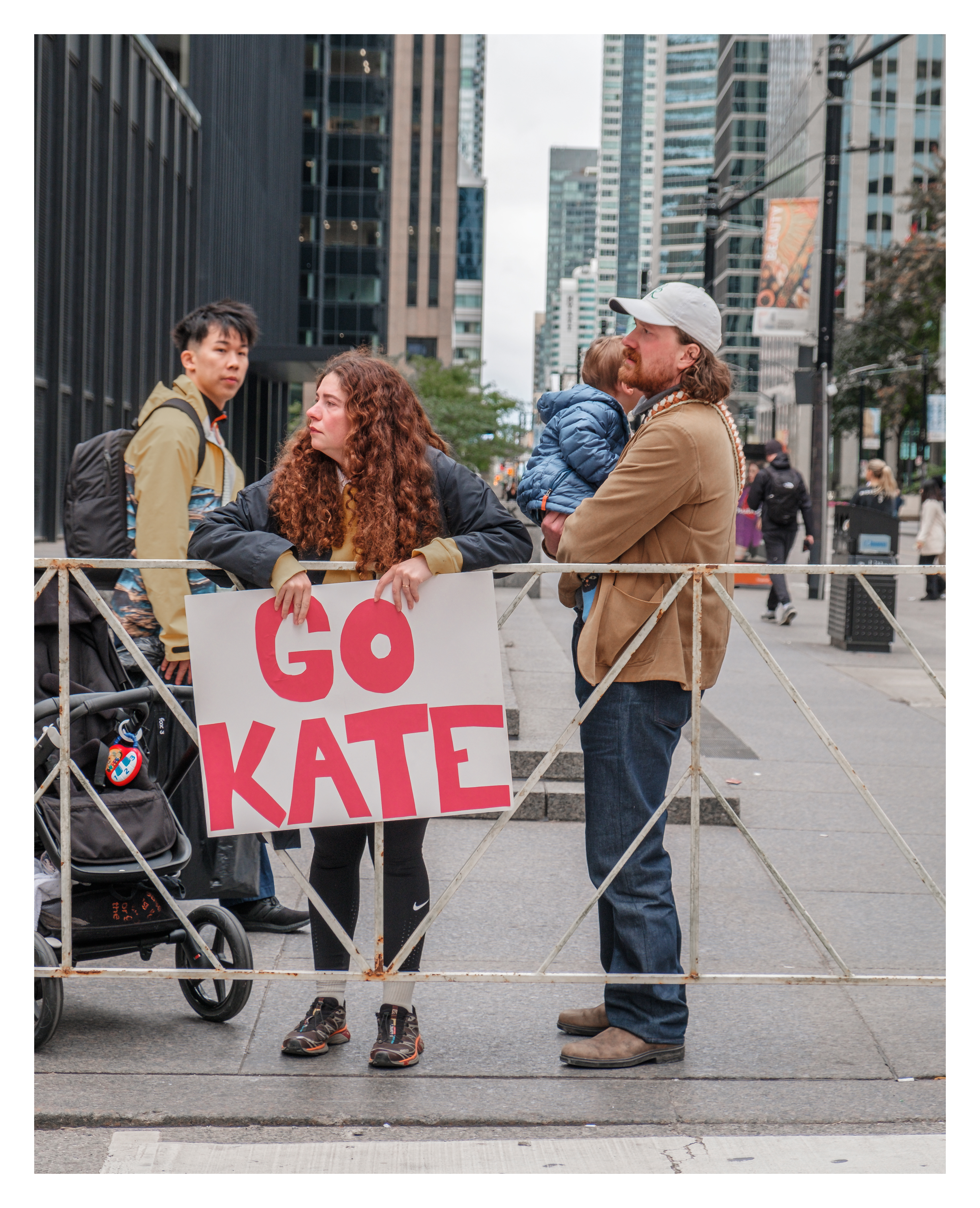 Family cheering with bold “Go Kate” sign behind safety barricades in downtown Toronto, capturing family support during urban racing events.