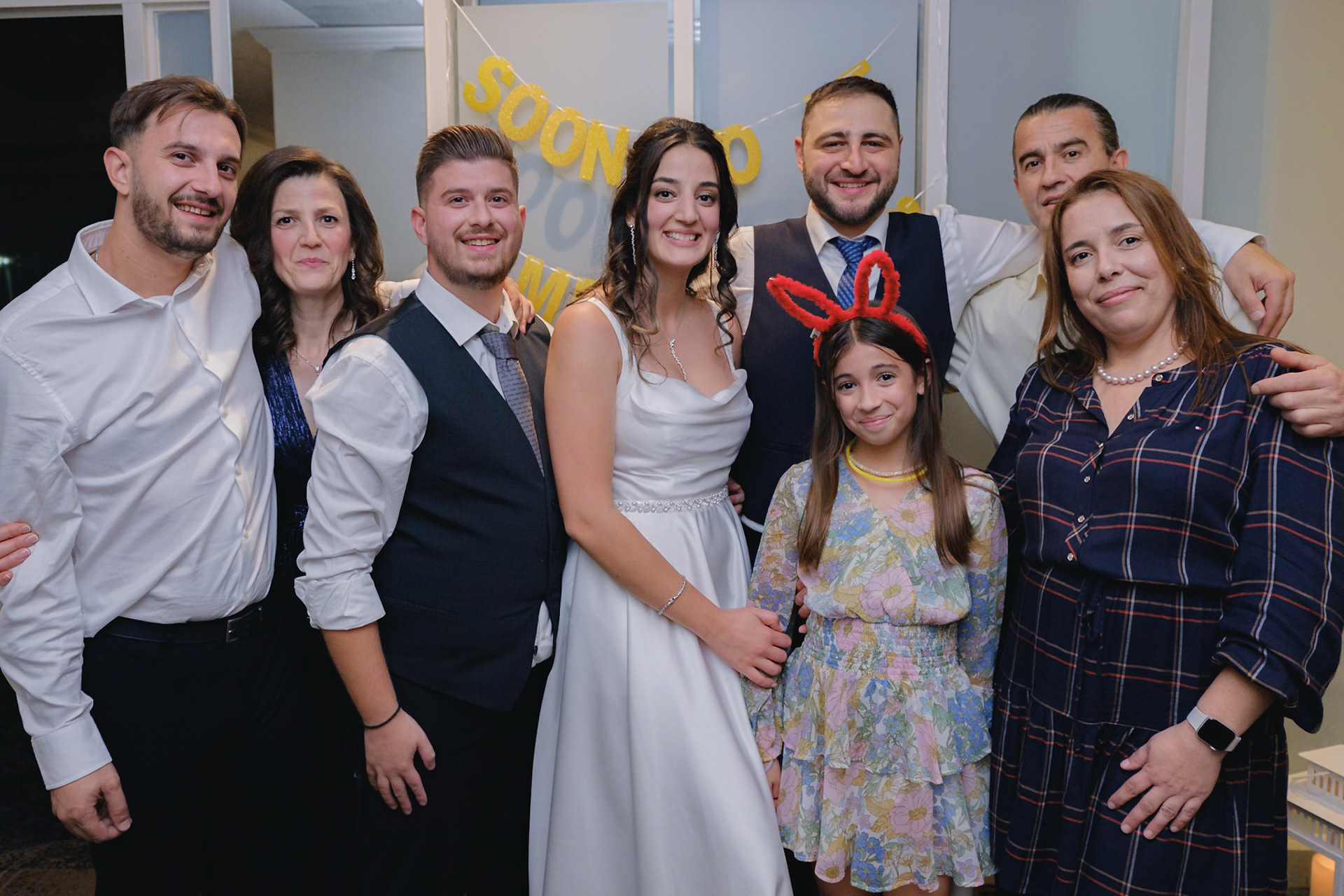 Bride surrounded by family and friends, posing in front of a "Soon to Be" banner at Toronto engagement celebration