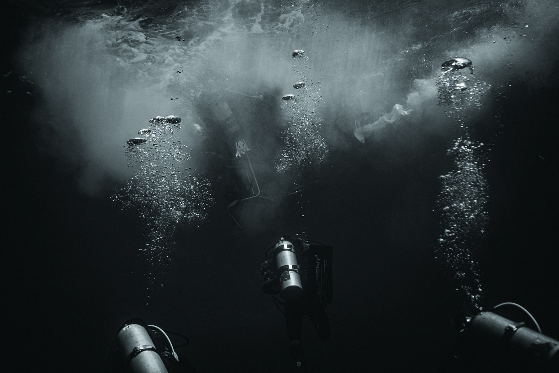 Divers trying to climb onto a moving zodiac in rough seas