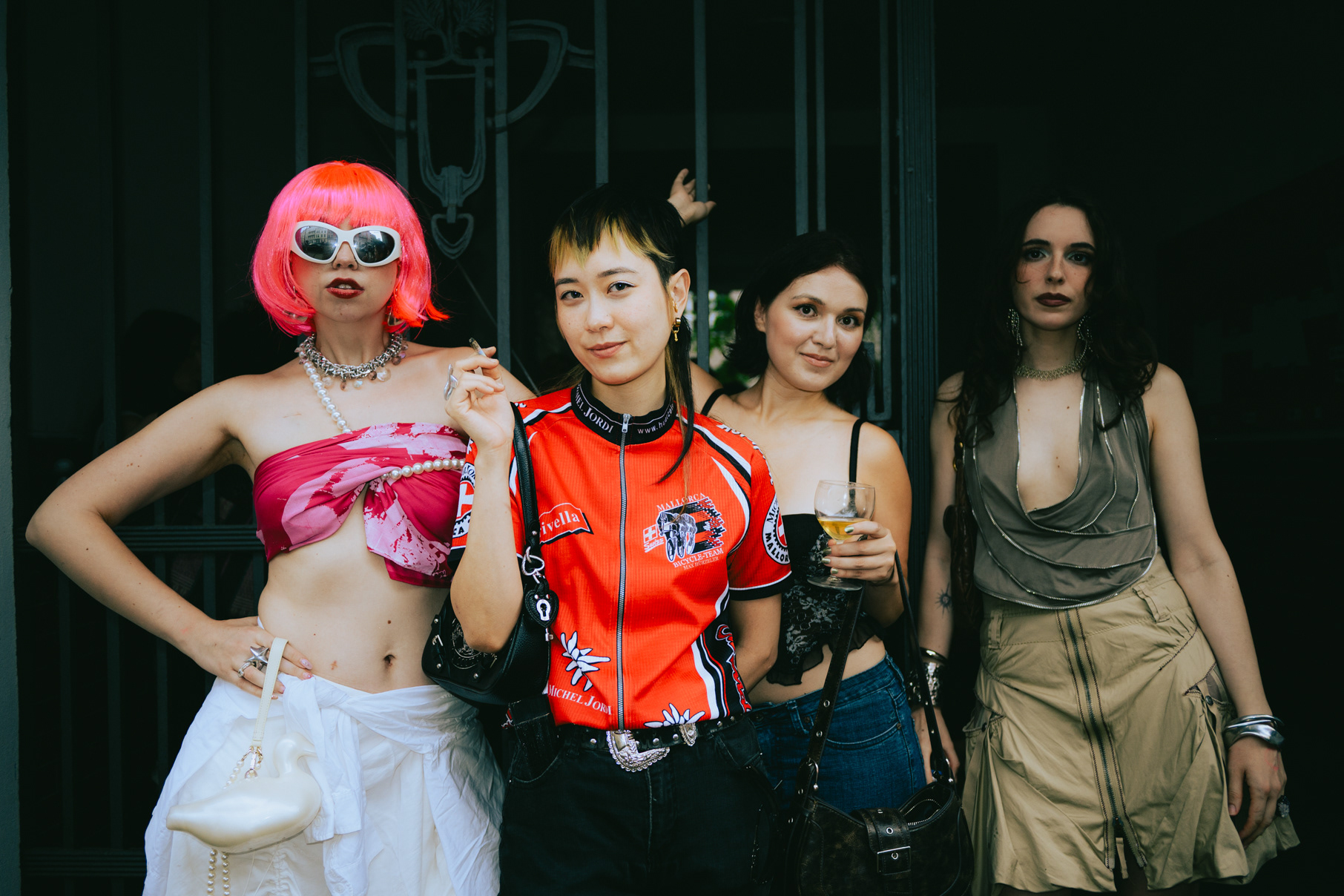 Four friends in eclectic party outfits, pink wig and orange jersey, at a Berlin fashion event