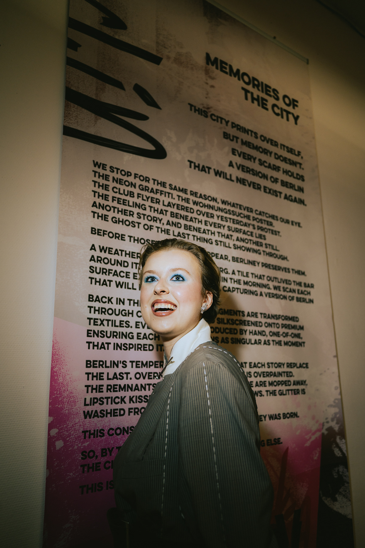 Portrait of a woman in front of an event poster wall at a Berlin fashion show