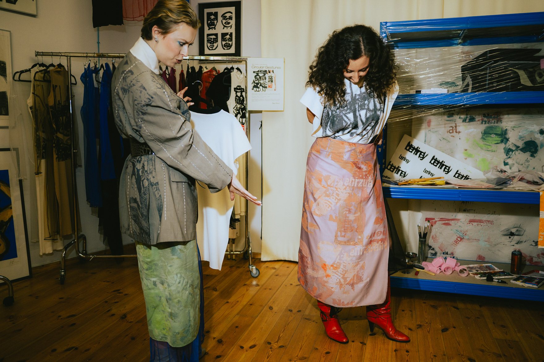 Fashion designer fitting a floral silk dress on a model backstage in Berlin