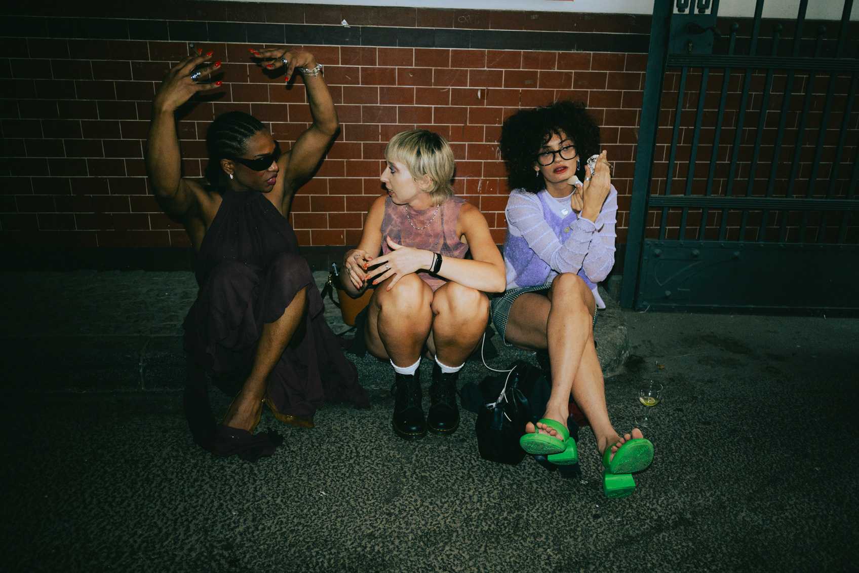Guests dancing and laughing against a brick wall at a Berlin fashion event afterparty