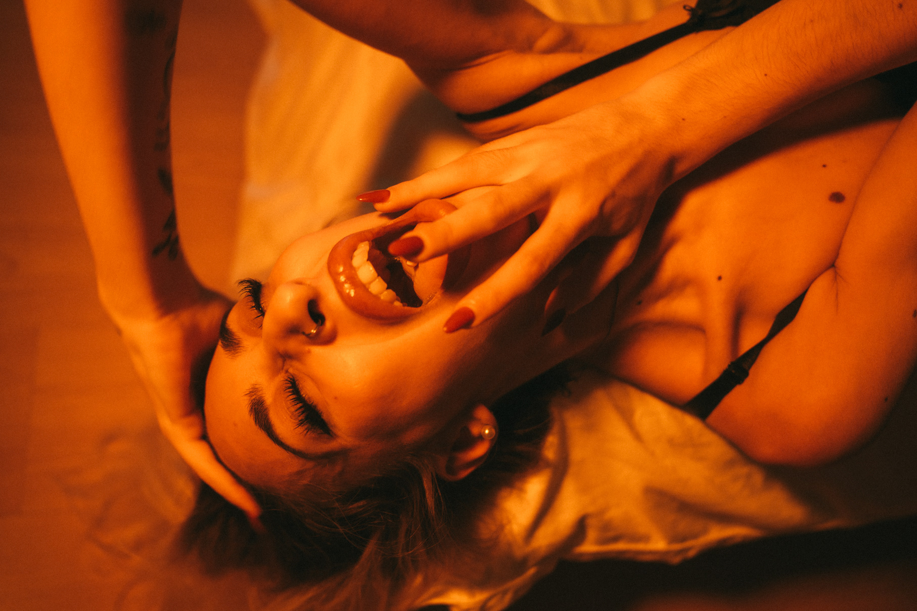 Boudoir portrait with head tilted back under warm orange light in Bangkok