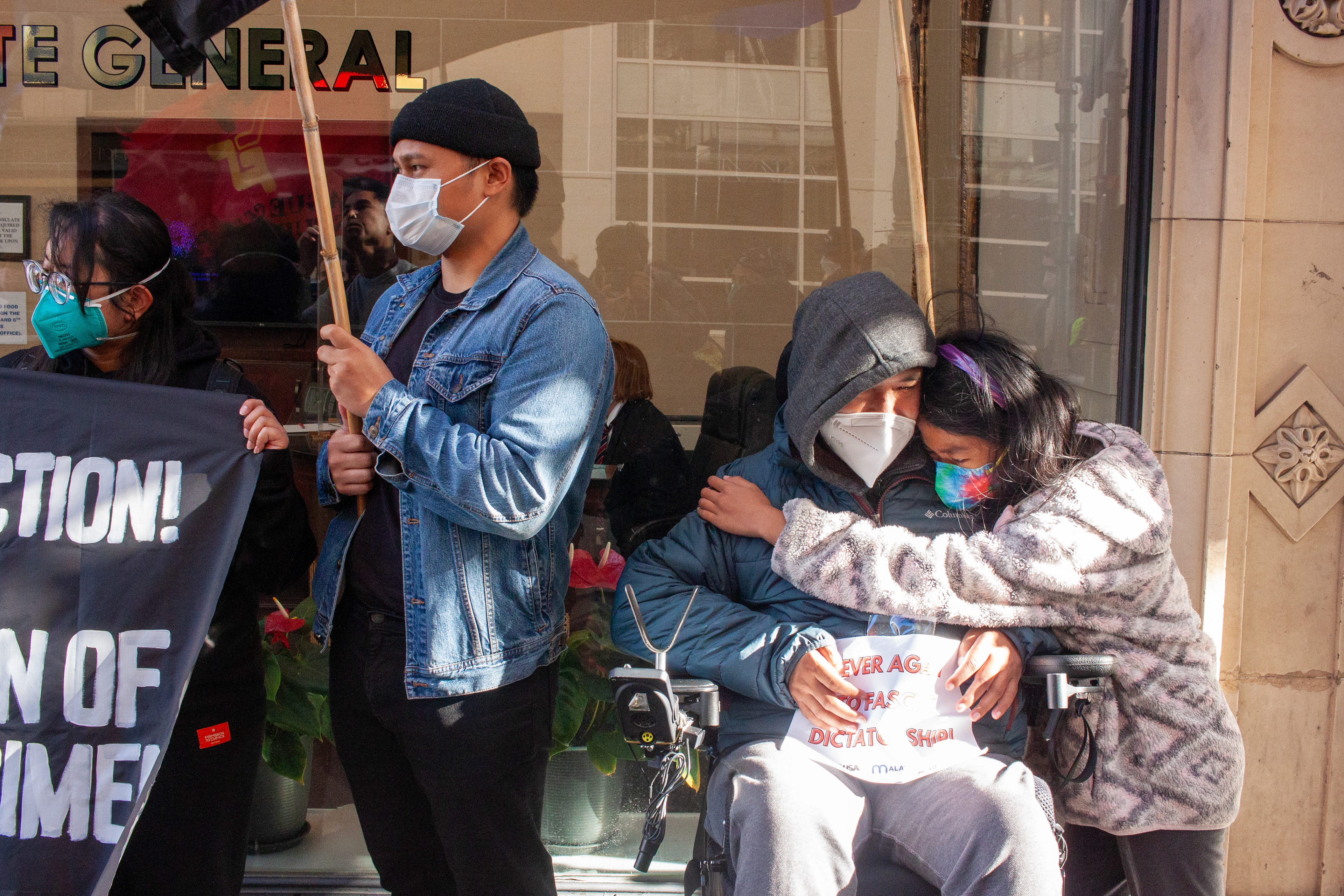 A girl hugs her grandfather after he gave a speech outside the Philippine Consulate in San Francisco during an anti-Marcos Jr. protest on May 13, 2022; her grandfather was affected by the policies of Ferdinand Marcos Sr. Photo by Klyde Java.