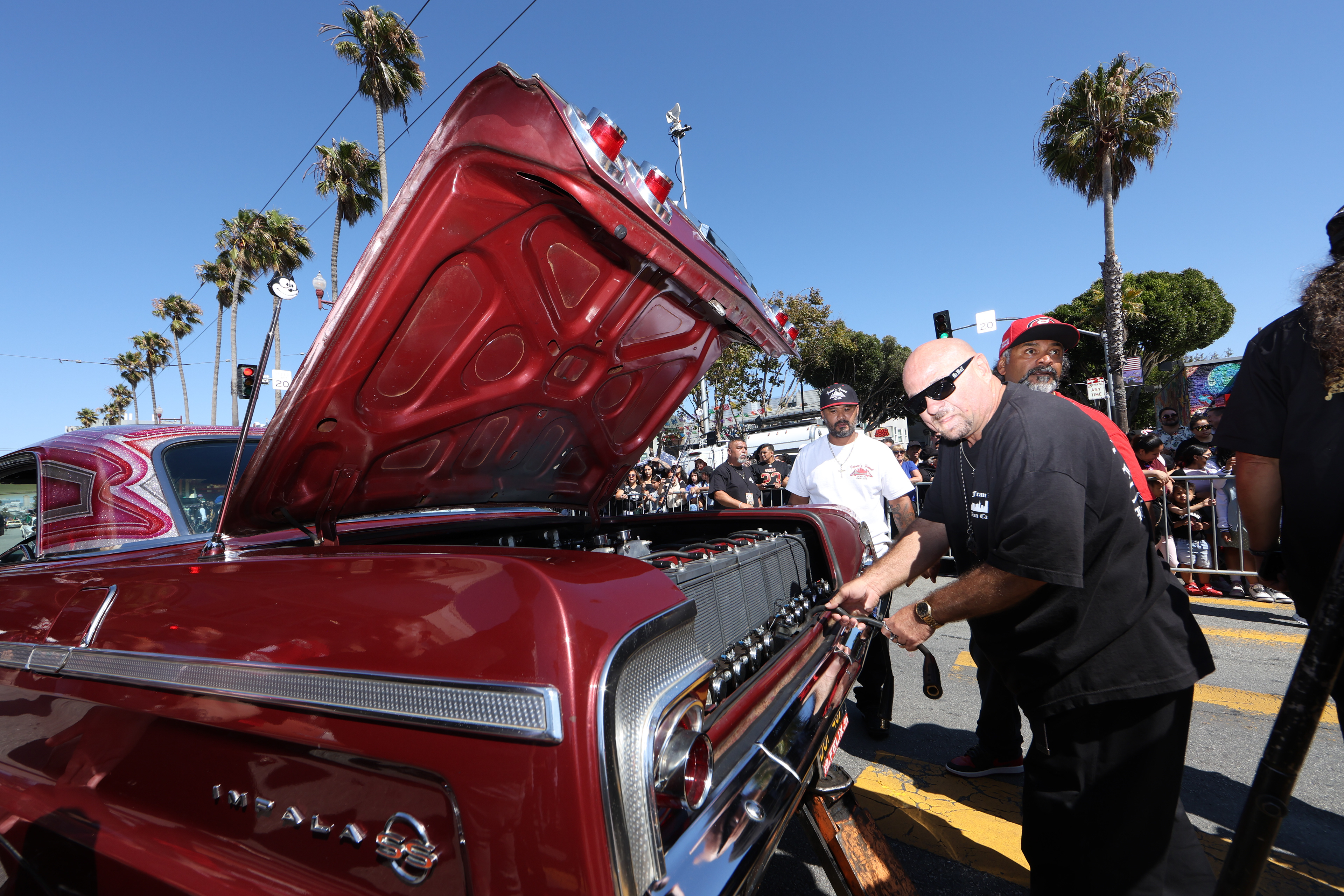 Members of the Nor Cal Car Club investigate the hydraulics of a broken lowrider during the San Francisco Lowrider Parade on Sept. 20, 2025. Photo by Klyde Java.
