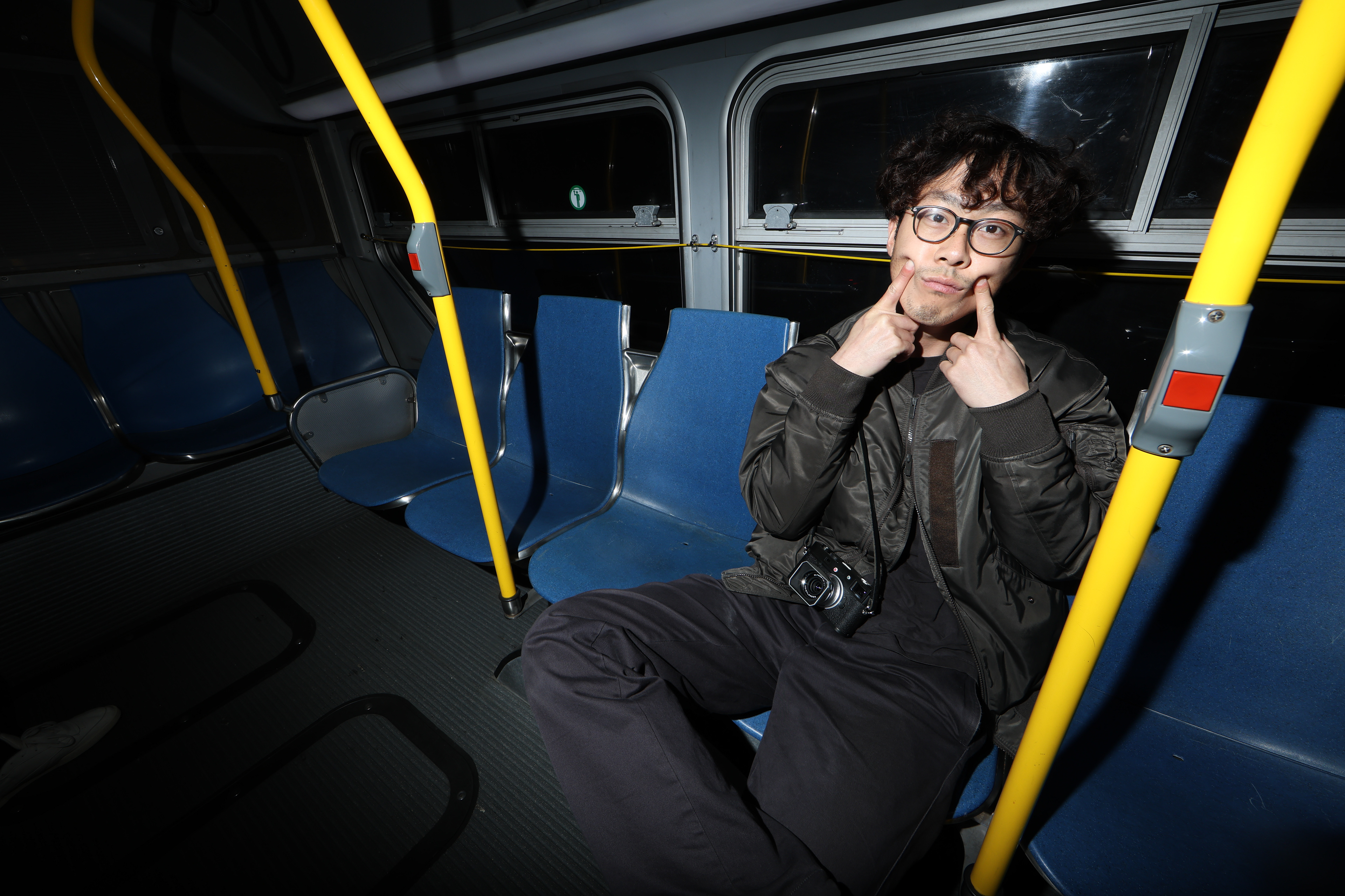 Photographer Zhenhui Wu fake smiles on the 5 Fulton Muni bus on Feb. 9, 2026. Photo by Klyde Java.