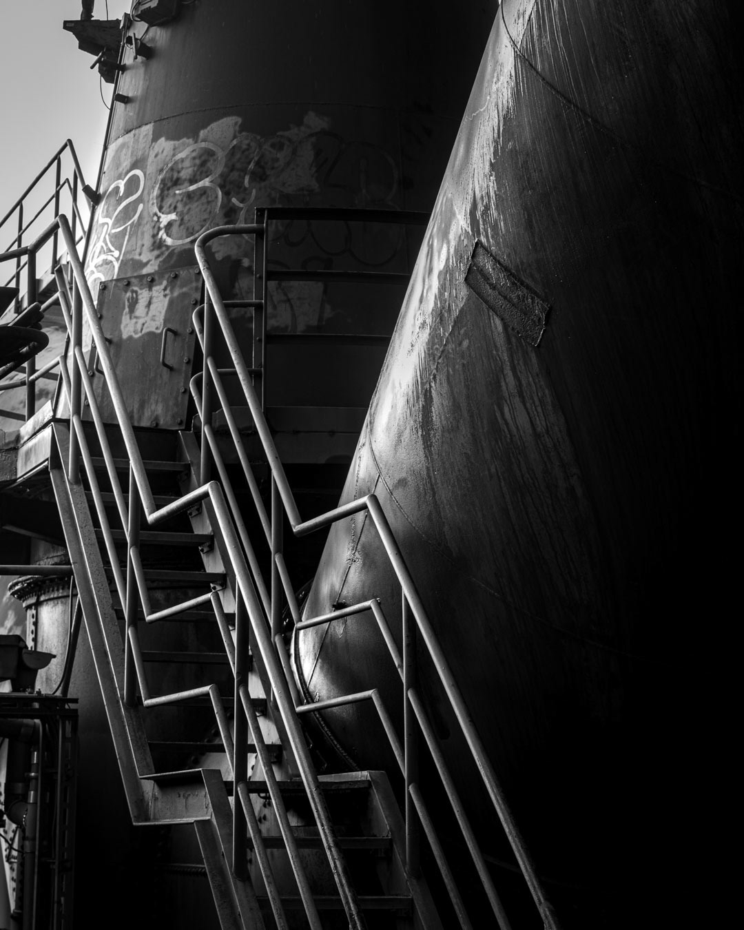 Steel Ascend — Industrial stairs vanishing into shadow, Duisburg.