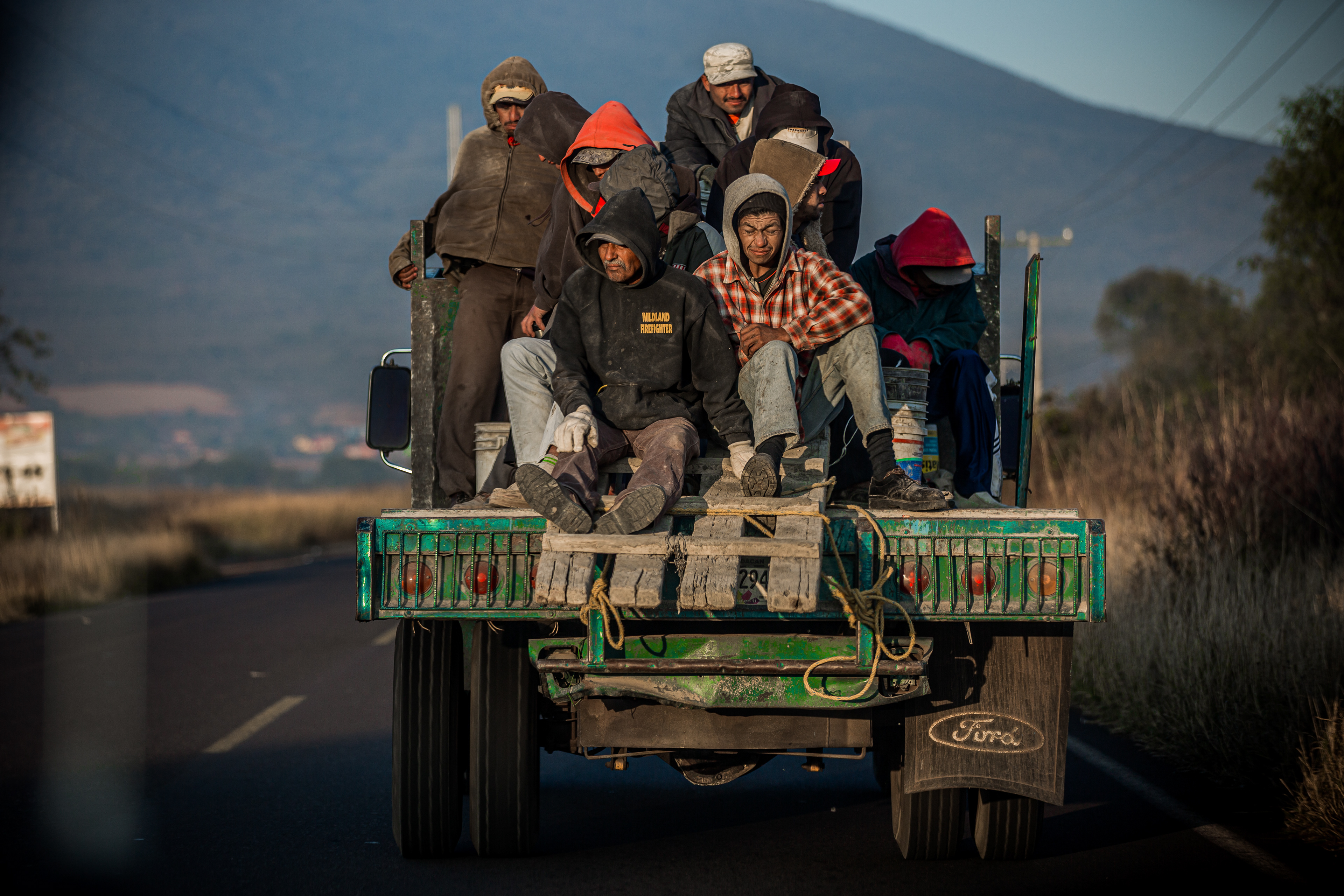 Labor workers in heading to work, hitching a ride on the back of a truck Michoacán | Mexico 