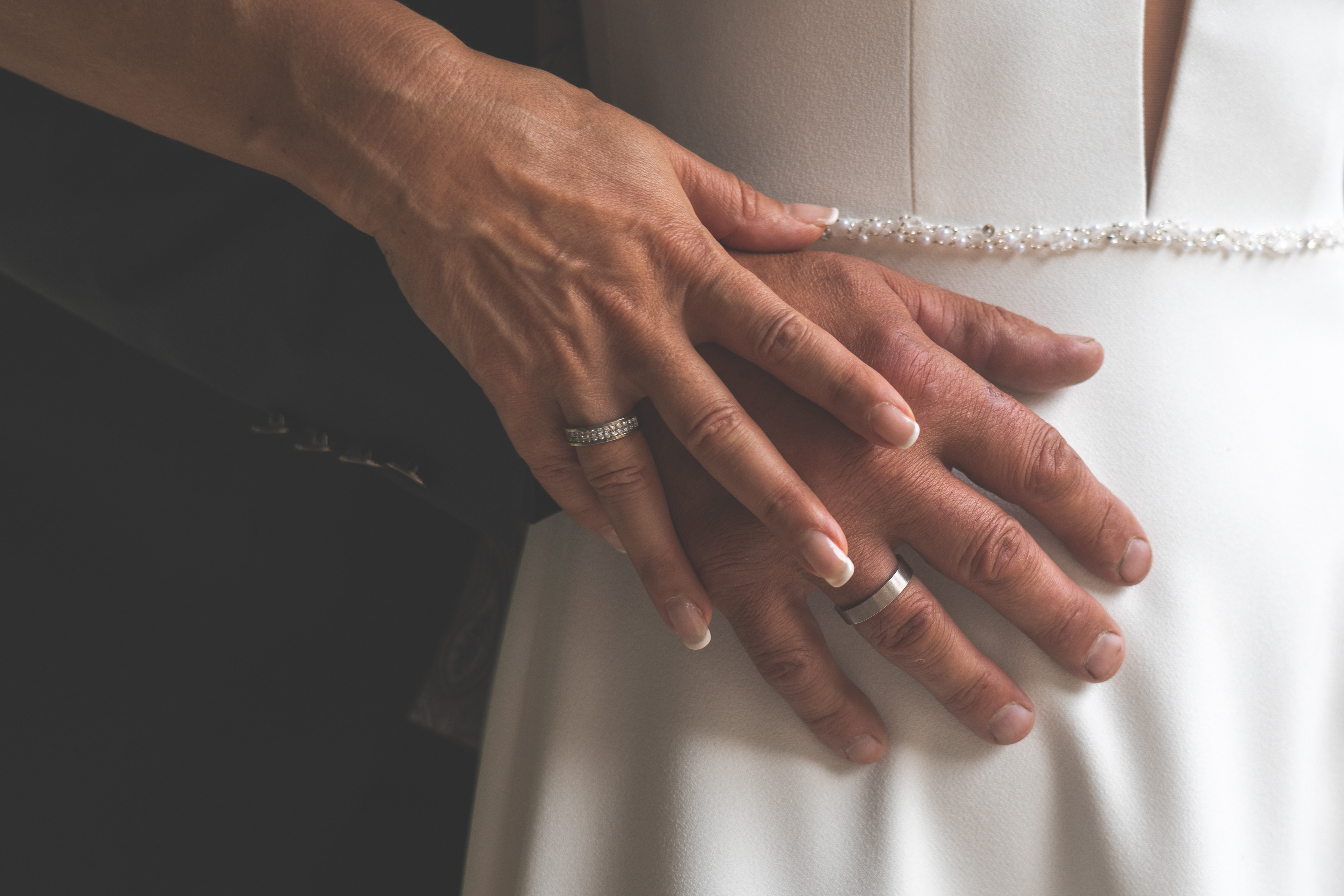 Veronika Rauch - Haende mit Eheringen auf Hochzeitskleid