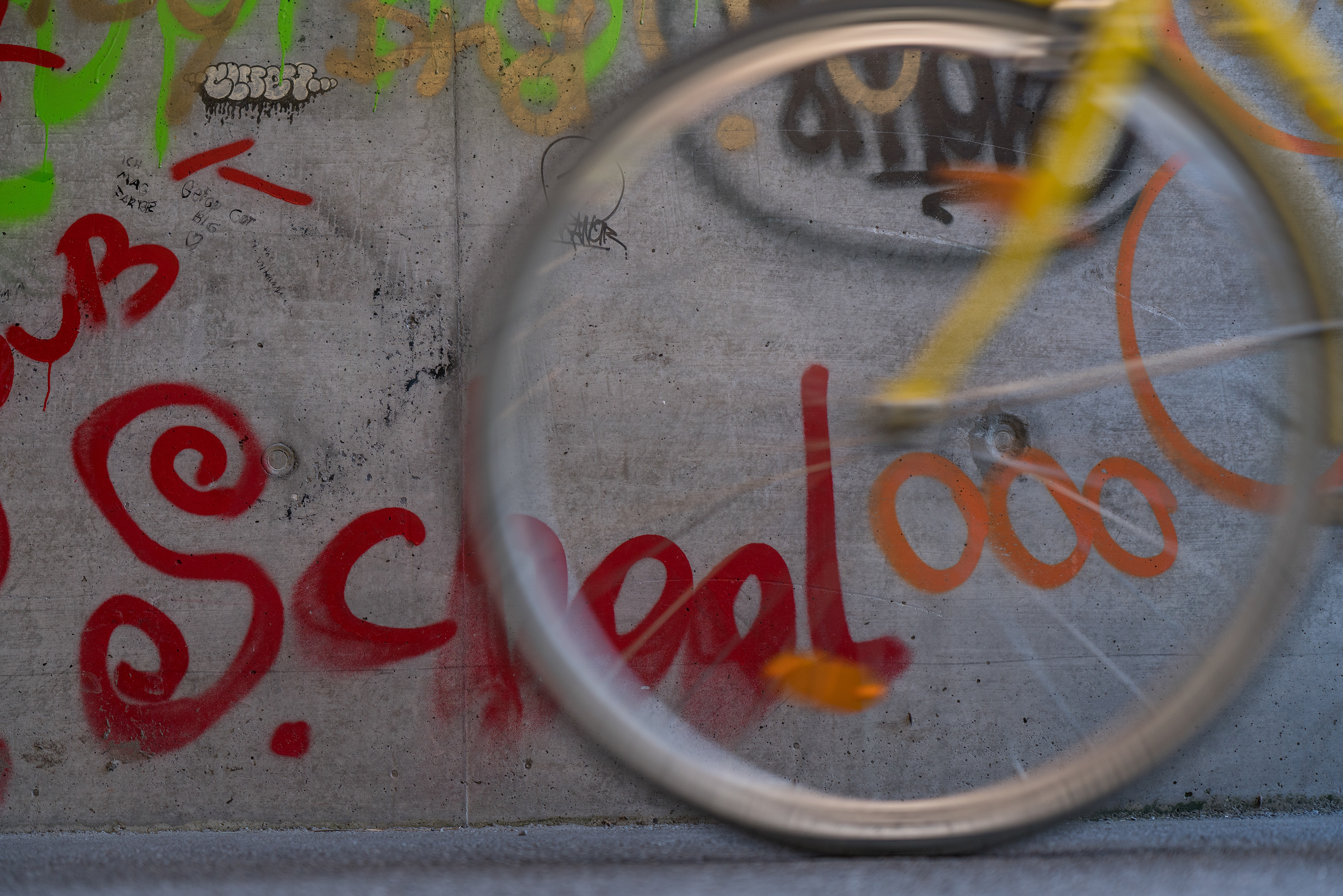 Veronika Rauch - fahrendes gelbes Rad mit Graffitis an der Wand