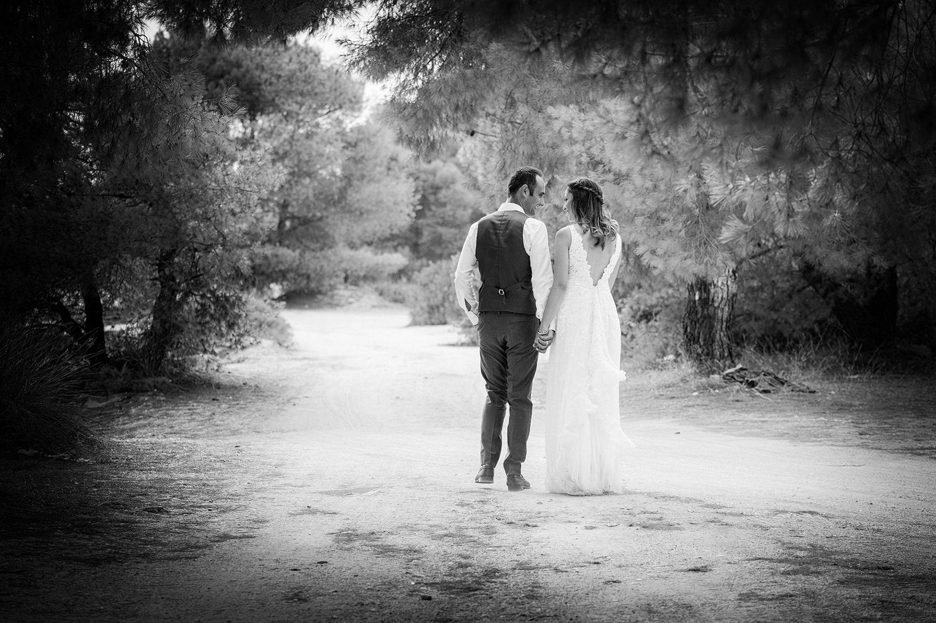 Ρομαντικό περπάτημα του ζευγαριού χέρι-χέρι στον δρόμο σε παραλιακό τοπίο στη Χαλκιδική- φωτογράφηση next day γάμου,       Romantic walk of the couple hand in hand on the street in a coastal landscape in Halkidiki - next day wedding photoshoot      