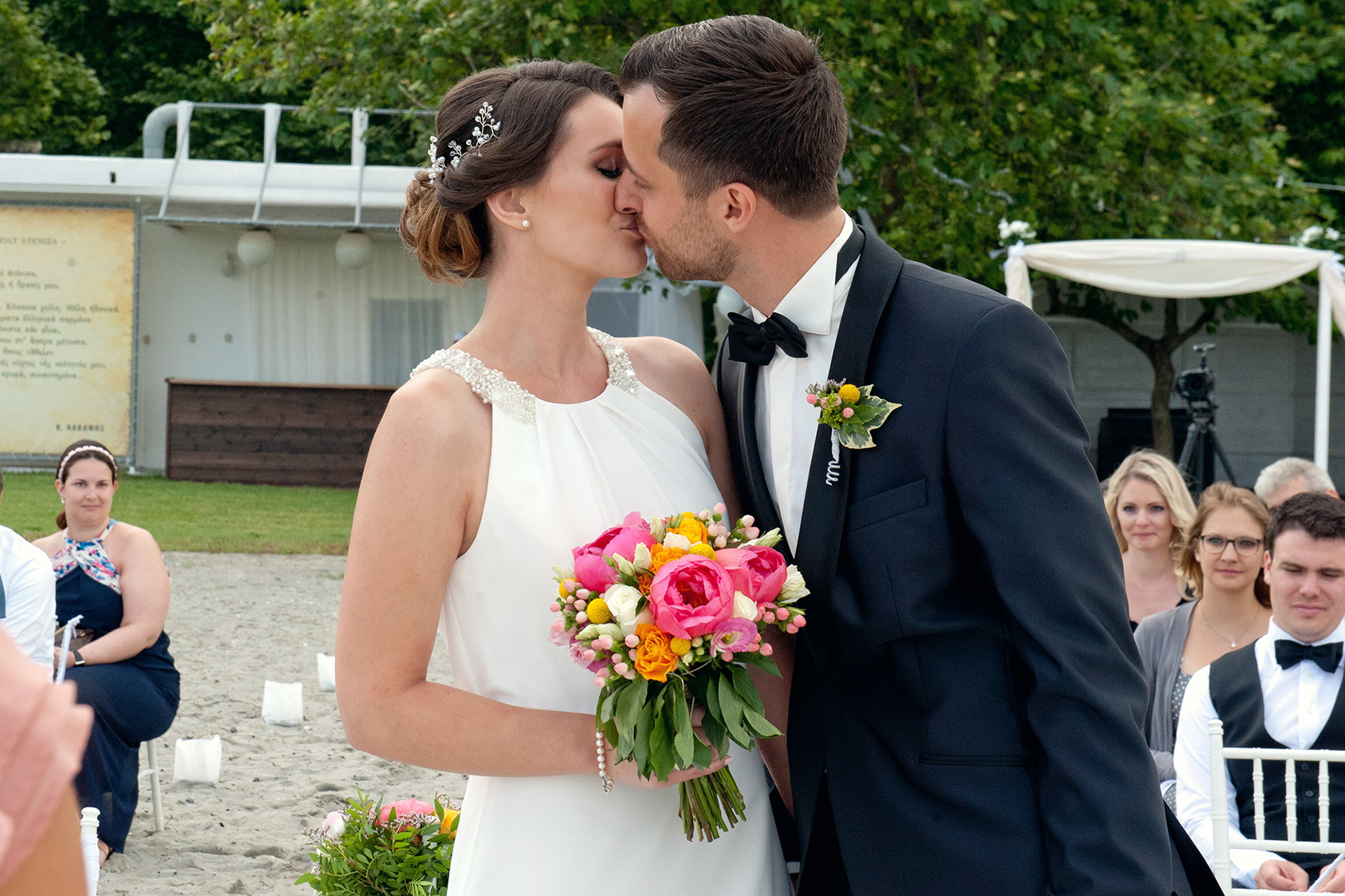 Η νύφη και ο γαμπρός φιλιούνται κατά τη διάρκεια της τελετής στην παραλία του Λιτοχώρου.  The bride and groom share a kiss during their beach wedding ceremony in Litochoro.