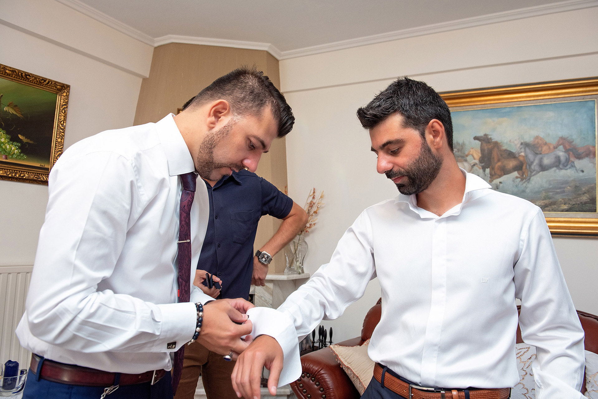 Ο αδερφός βοηθά τον γαμπρό να ντυθεί για τον γάμο. Groom’s brother helping him get dressed for the wedding.