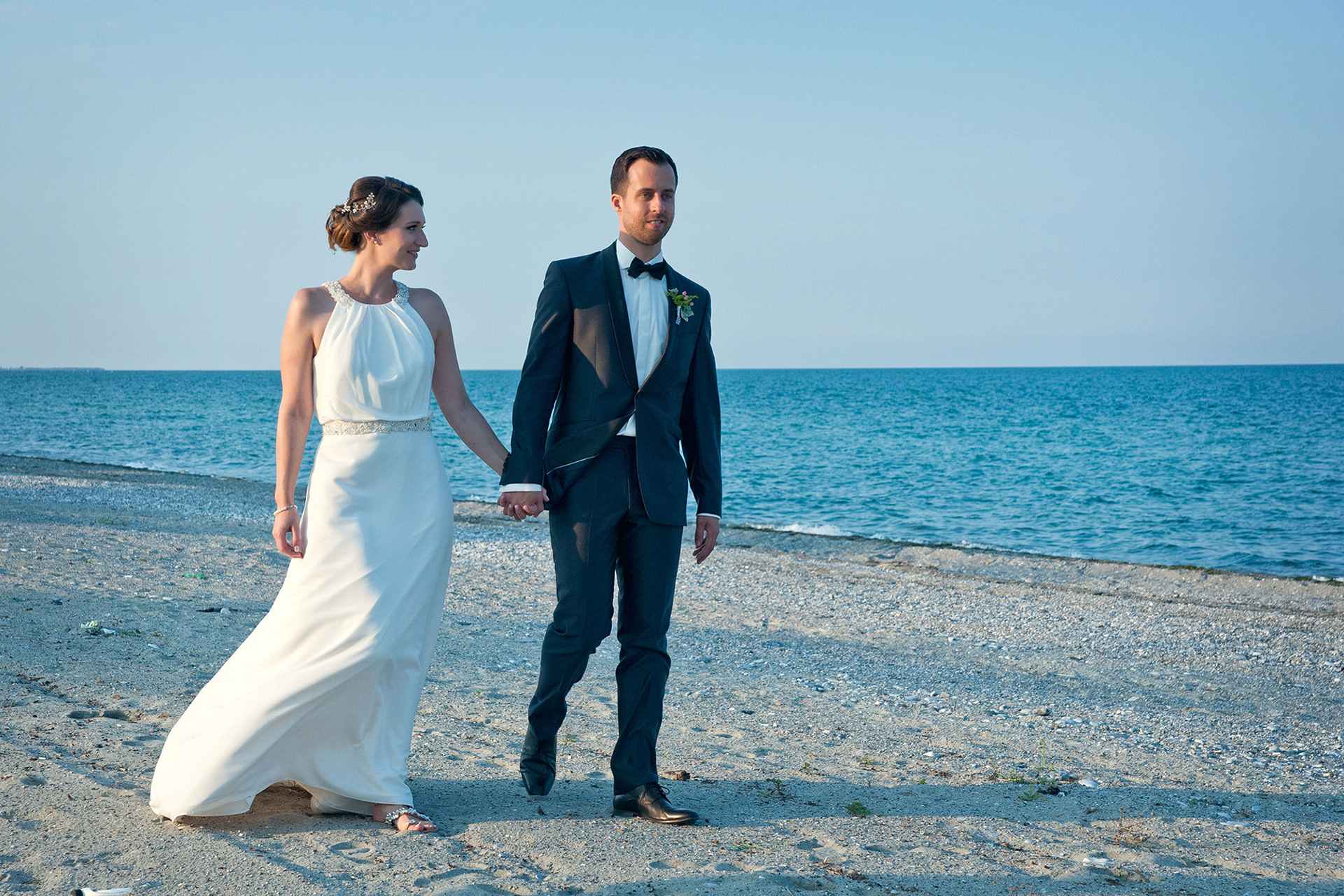 Το ζευγάρι περπατά πιασμένο χέρι χέρι στην άκρη της ακτής.  The couple walks hand in hand along the shoreline.