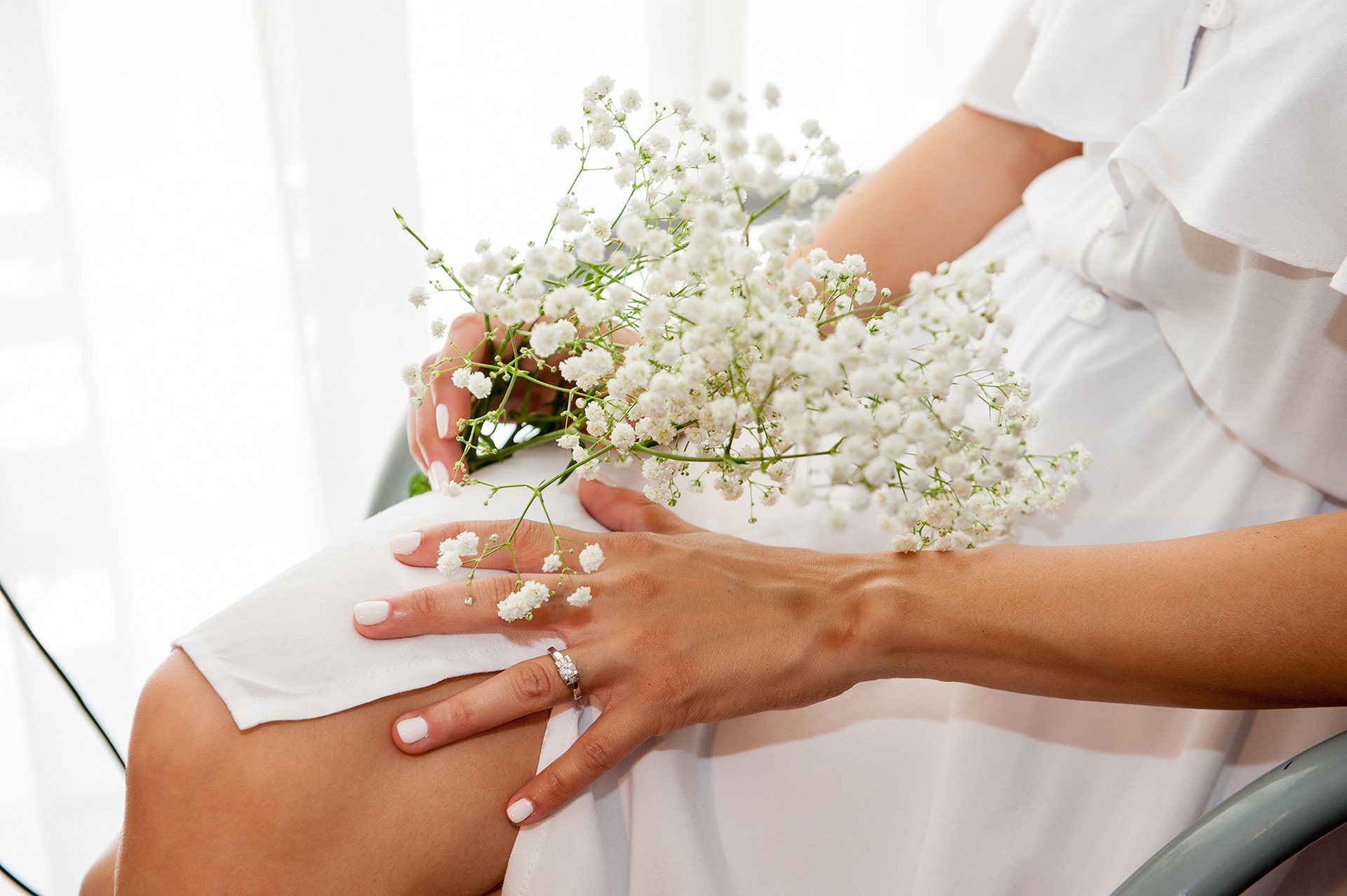 Λεπτομέρεια από τα χέρια της νύφης με μικρή ανθοδέσμη, ρομαντική φωτογράφιση γάμου με φυσικό φως.,     Detail of the bride's hands with a small bouquet, romantic wedding photography with natural light. 