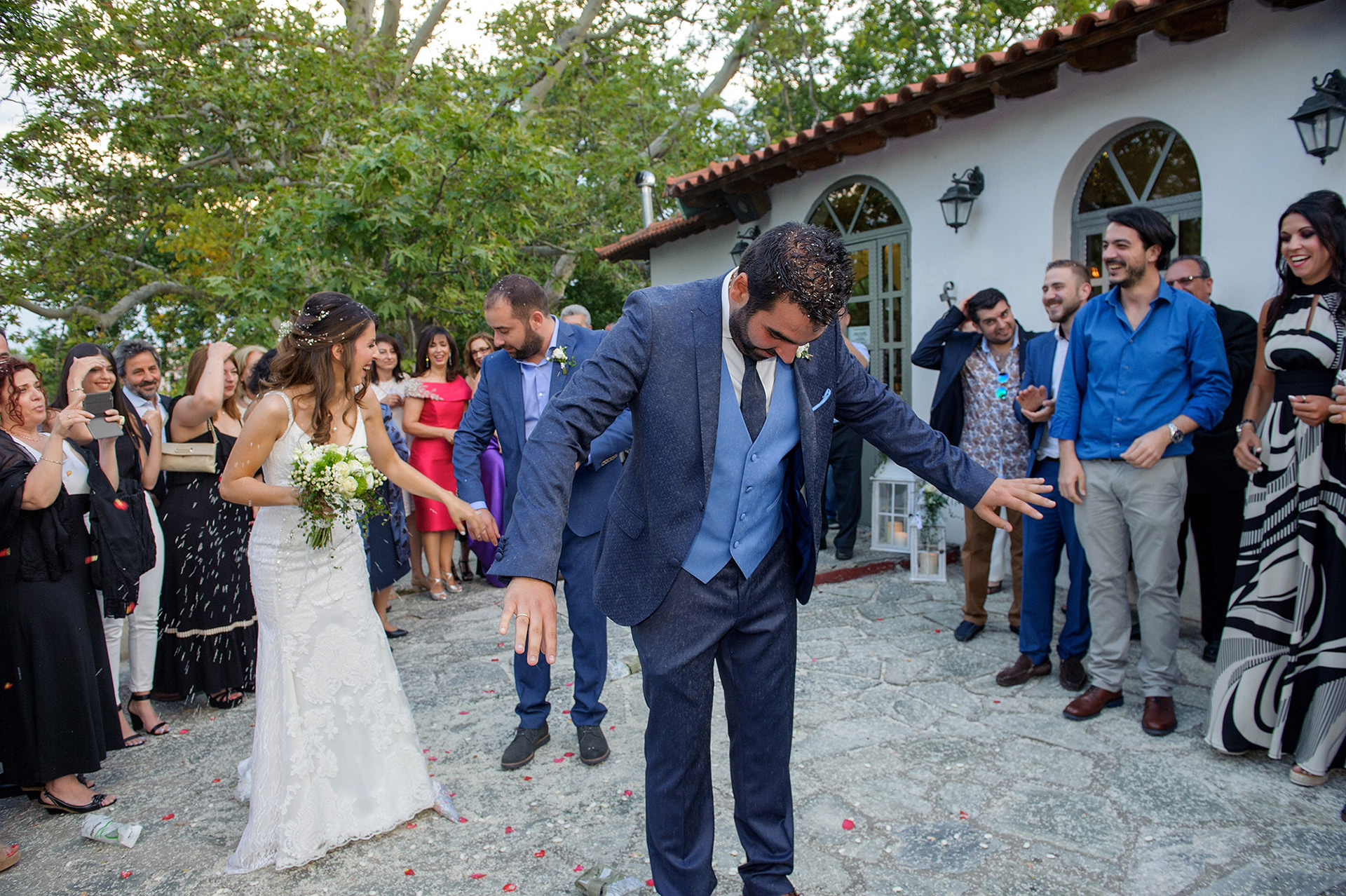 Το ζευγάρι βγαίνει από την εκκλησία, περιτριγυρισμένο από φίλους και συγγενείς που το χειροκροτούν.     The couple exits the church surrounded by friends and family clapping and celebrating.