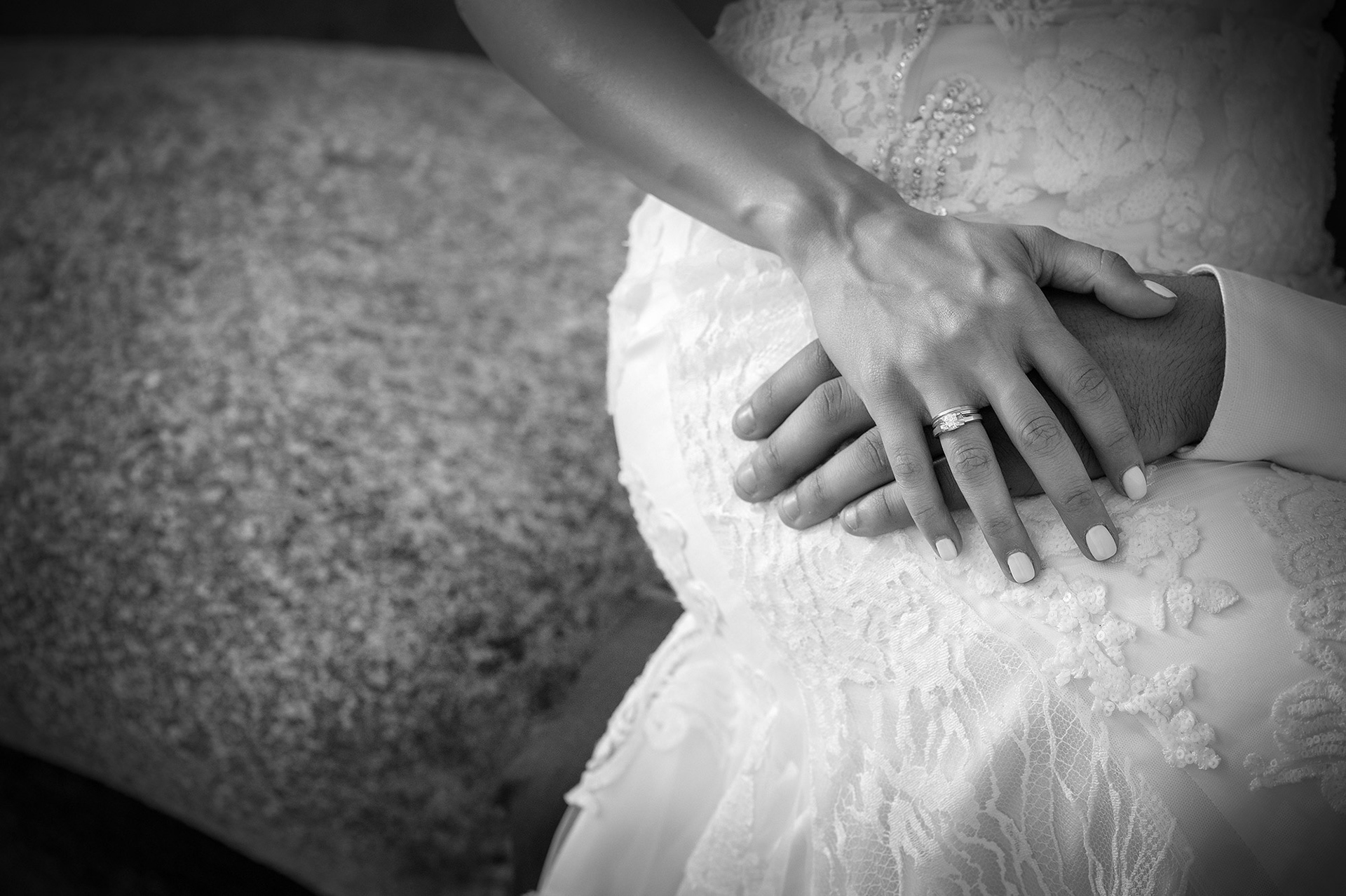 Κοντινή φωτογραφία των χεριών του ζευγαριού που κρατιούνται, αναδεικνύοντας τις βέρες τους. Close-up of the couple’s hands showing their wedding rings.