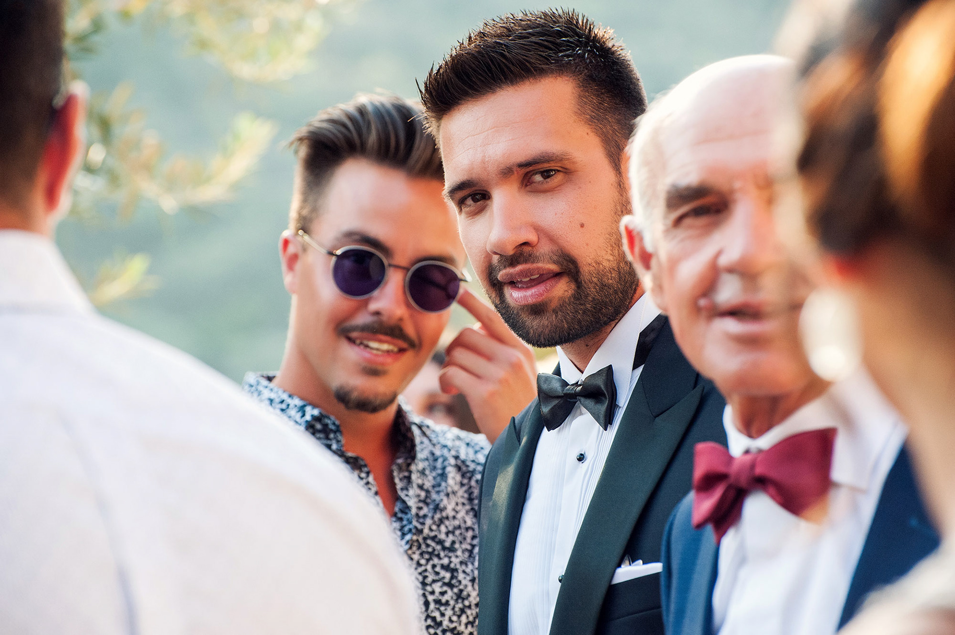 σε ρεπορταζιακό στυλ φίλοι μαζί με τον γαμπρό γελάνε έξω απο την εκκλησία – φωτογράφιση γάμου Χαλκιδική. , in a reportage style friends with the groom laugh outside the church – wedding photography Halkidiki.
