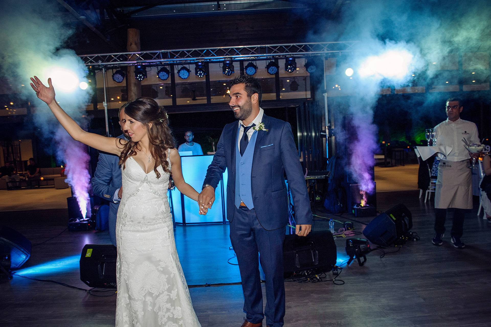 Το ζευγάρι κάνει εντυπωσιακή είσοδο στη δεξίωση, κρατώντας χέρια και χαιρετώντας τους καλεσμένους.      The couple makes a stunning entrance at the reception, holding hands and greeting the guests.