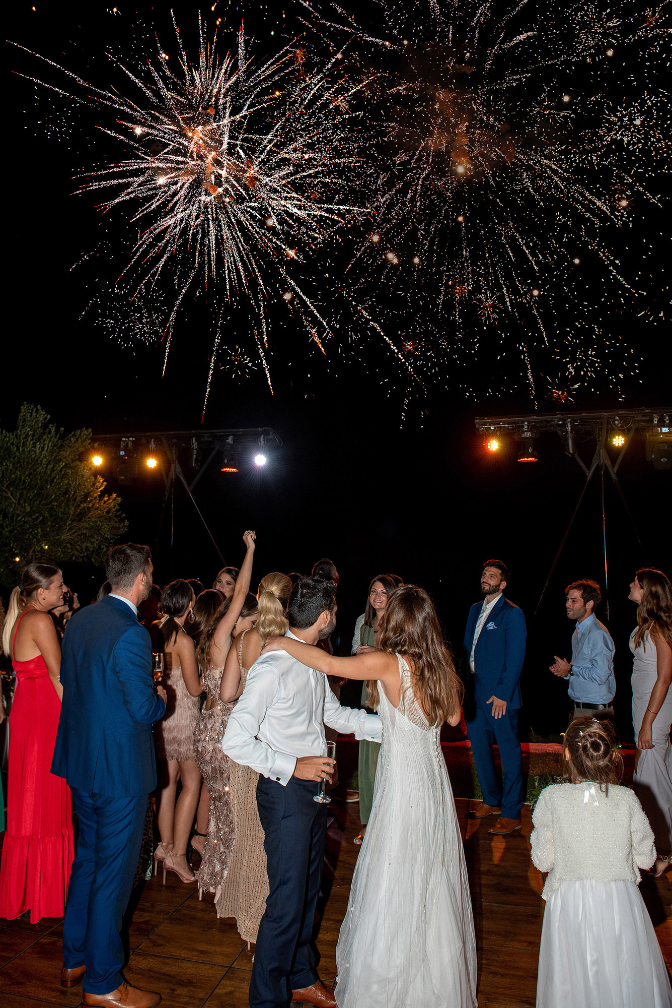 ζευγάρι κοιτάει αγκαλιασμένο τα πυροτεχνήματα στη δεξίωση του γάμου του, Couple embraces and watches fireworks at their wedding reception