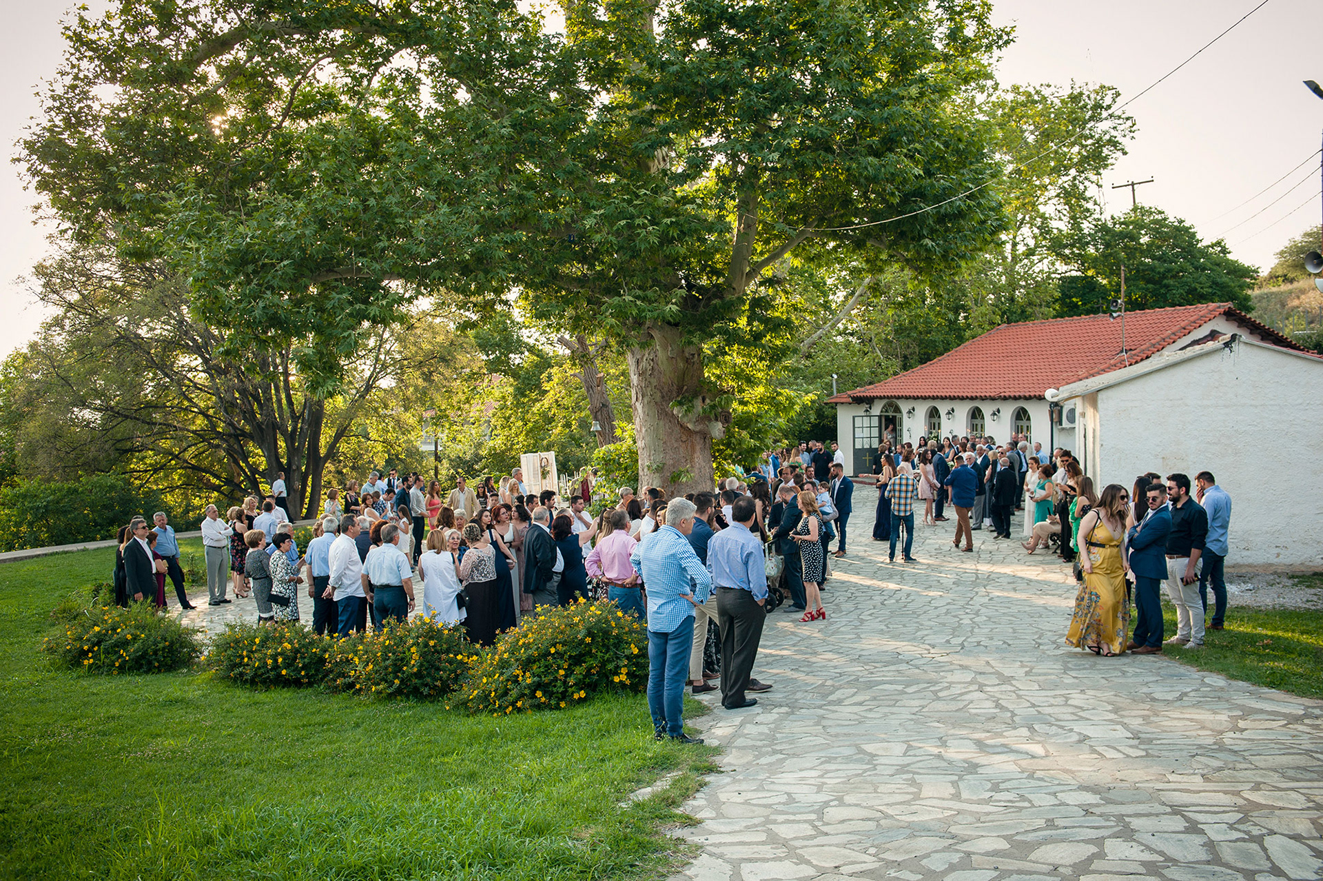Οι καλεσμένοι συγκεντρωμένοι έξω από το εκκλησάκι της Αγίας Τριάδας στο Ρετζίκι Θεσσαλονίκης, λίγο πριν ξεκινήσει ο γάμος.     Wedding guests gathered outside Agia Triada church in Retziki Thessaloniki, moments before the ceremony begins.