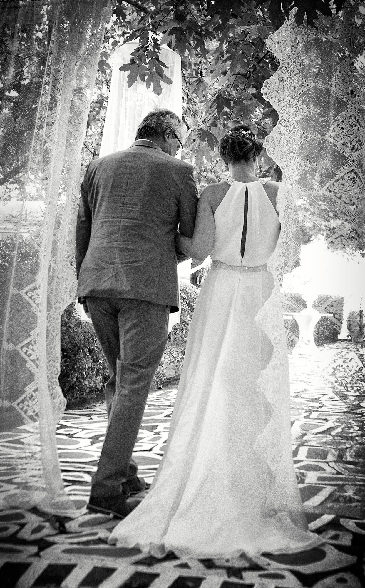 Ασπρόμαυρη φωτογραφία της νύφης με τον πατέρα της λίγο πριν την είσοδο στην τελετή.  Black and white photo of the bride and her father just before entering the wedding ceremony.