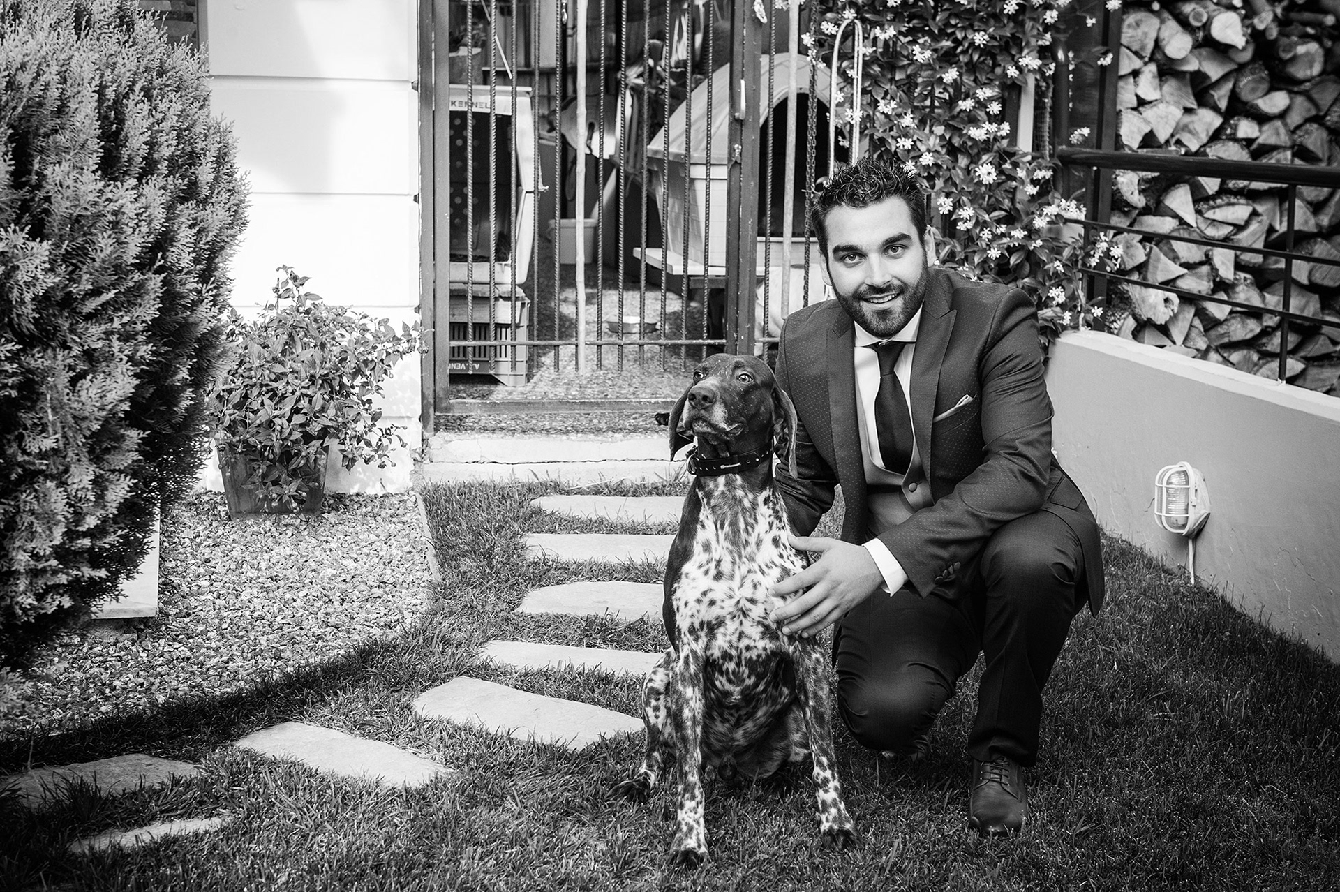 Ο γαμπρός ποζάρει με το σκυλί του σε ασπρόμαυρη φωτογραφία, ιδιαίτερη και συναισθηματική στιγμή πριν το γάμο.    The groom posing with his dog in a black and white photo, emotional and personal pre-wedding moment.