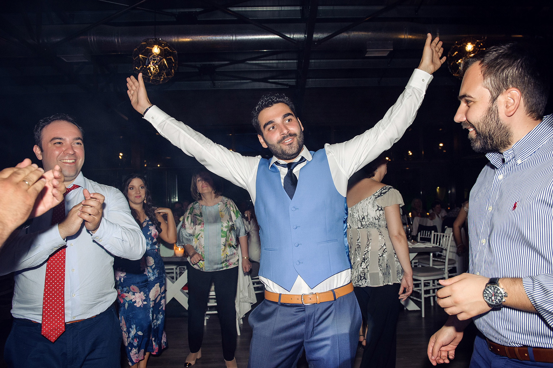Ο γαμπρός σηκώνει τα χέρια του ψηλά και χορεύει με ενθουσιασμό στο πάρτι του γάμου.       The groom raises his arms and dances with excitement during the wedding party.