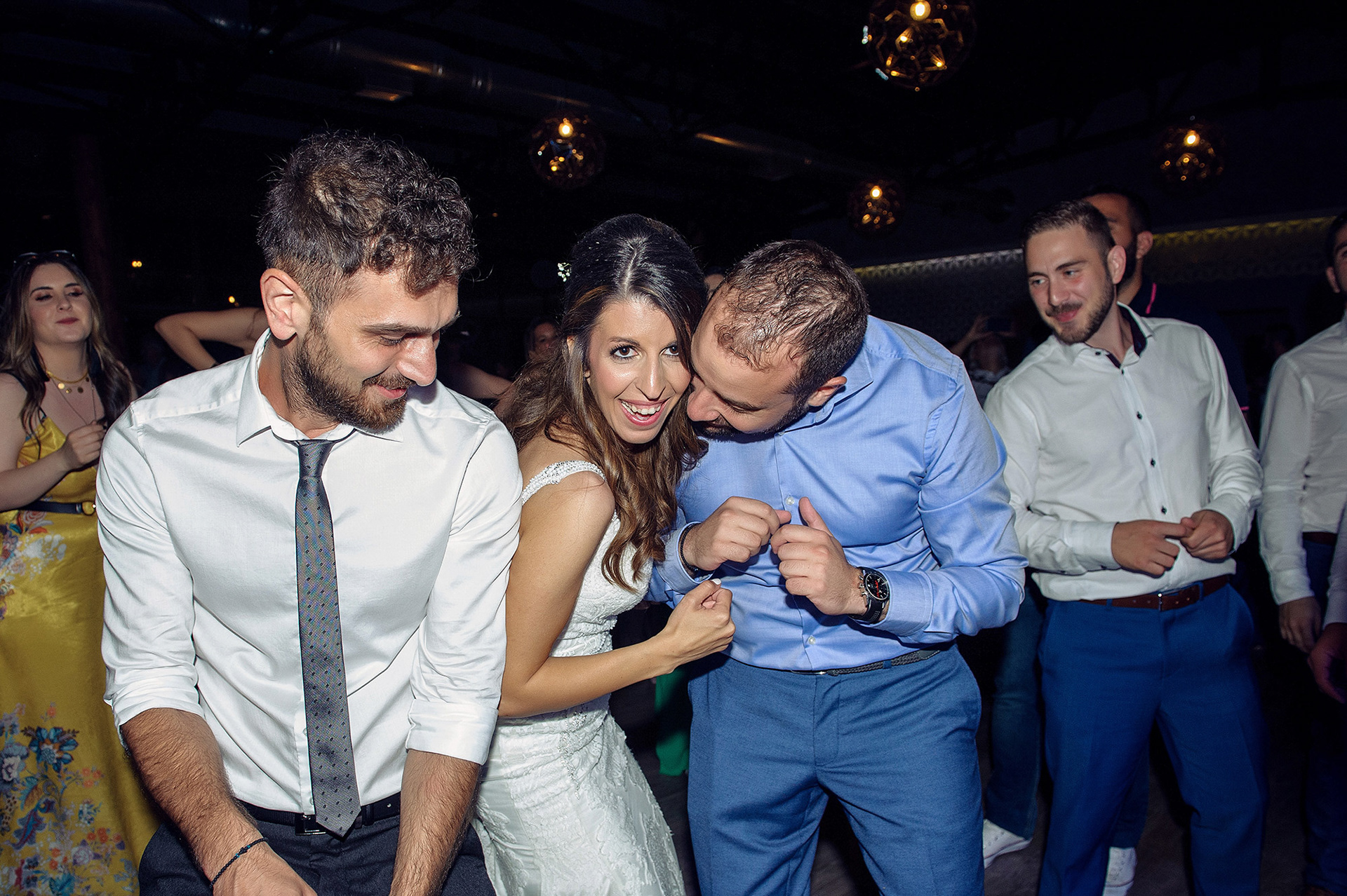 Η νύφη και ο γαμπρός χορεύουν με τους καλεσμένους τους γεμάτοι χαρά στη δεξίωση του γάμου.   The bride and groom dance joyfully with their guests during the wedding reception.
