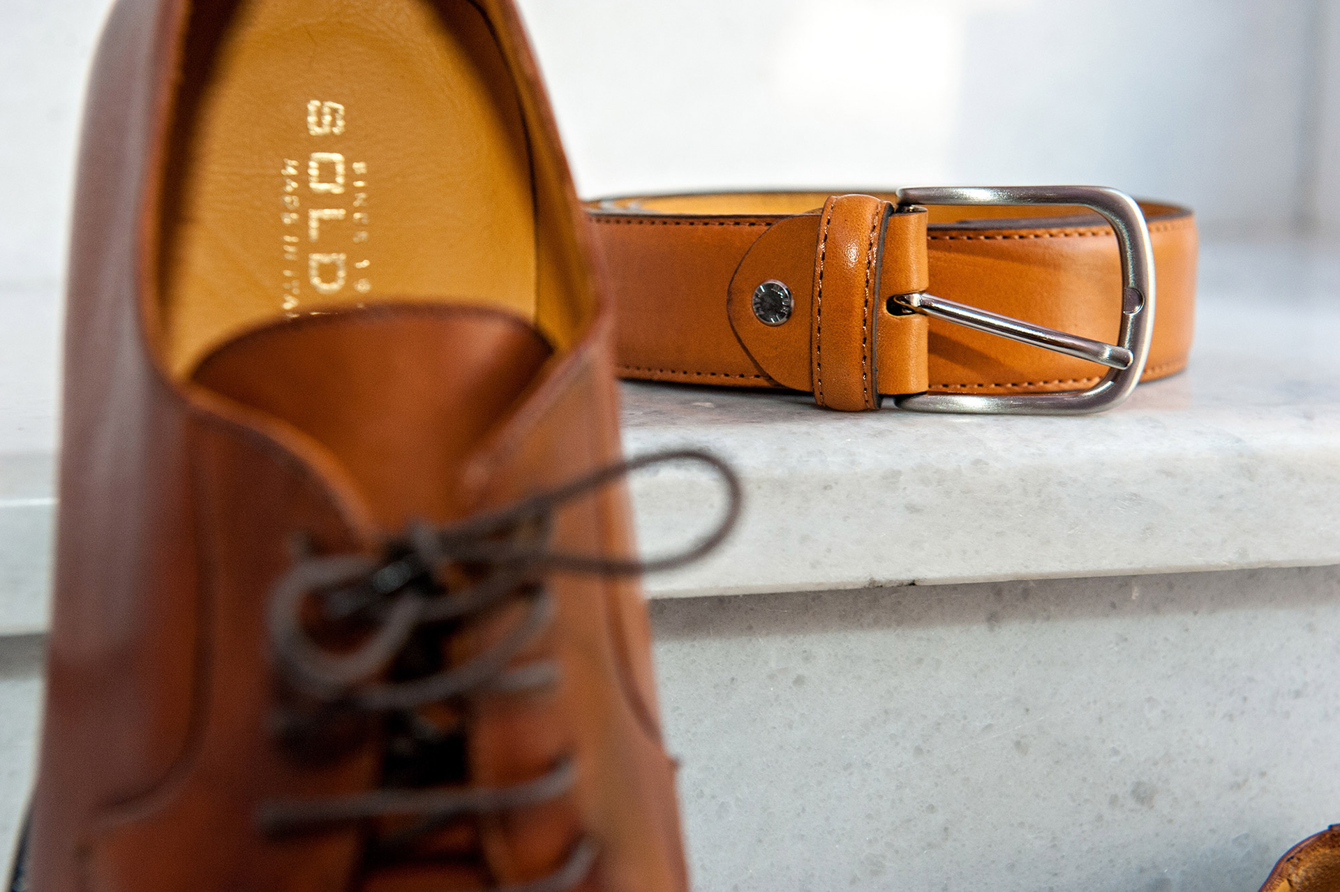 Καφέ δερμάτινη ζώνη και παπούτσια του γαμπρού, minimal φωτογράφιση προετοιμασίας γάμου.      Brown leather belt and groom’s shoes, minimalistic wedding preparation photography.