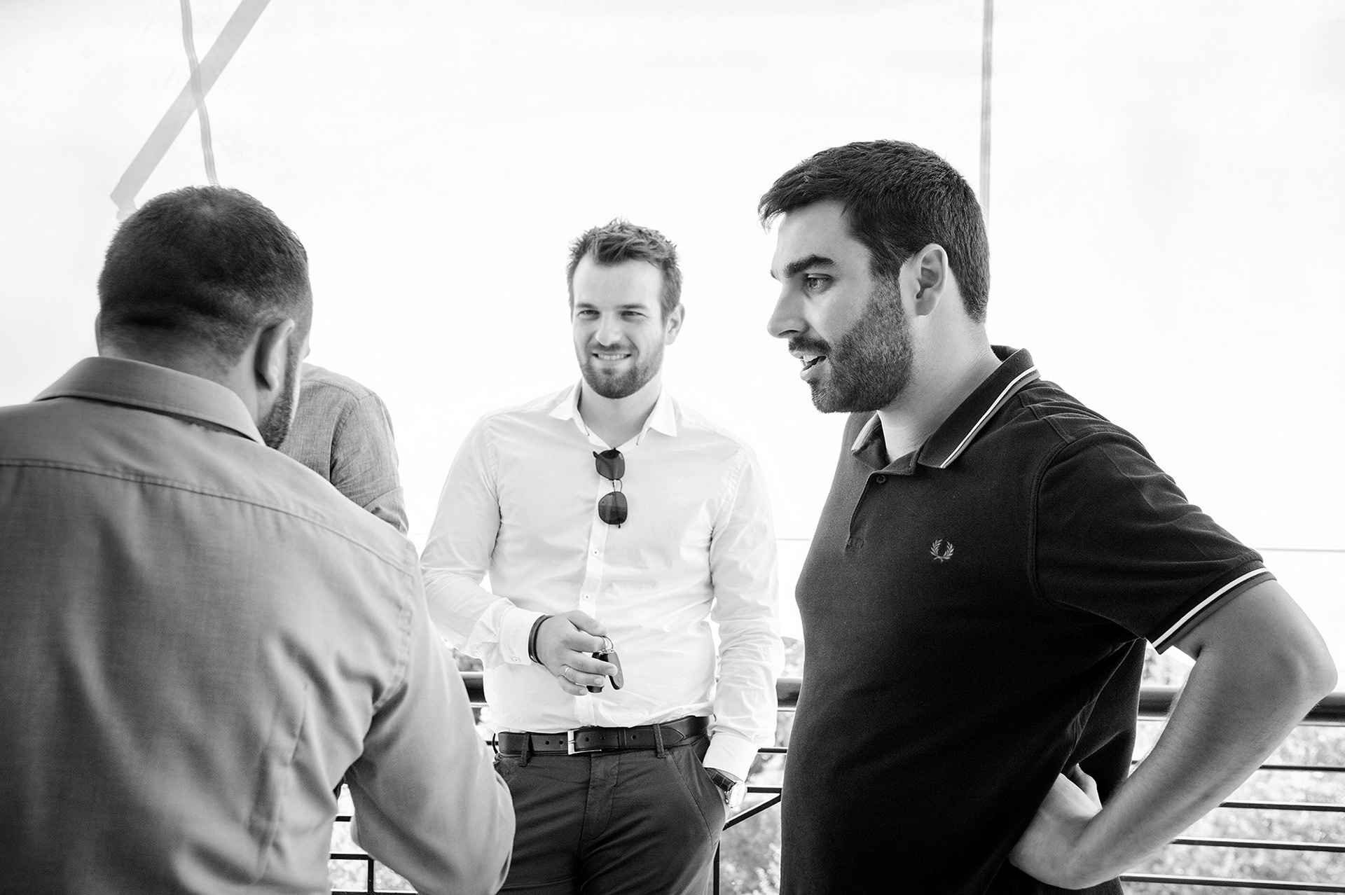 Ο γαμπρός και οι φίλοι του στη βεράντα, ασπρόμαυρο στιγμιότυπο με φυσικό φως και ανεμελιά.      Groom and friends on the balcony, black and white candid photo with natural light.