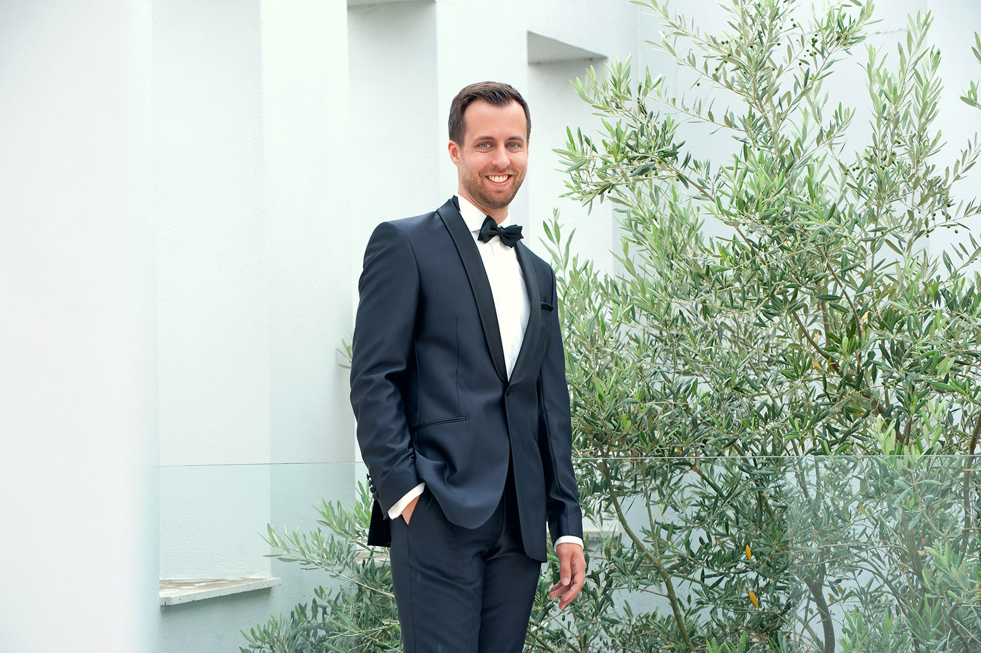 Ο γαμπρός ποζάρει χαμογελαστός με φόντο ελιές στο Λιτόχωρο.     The groom posing with a smile among olive trees in Litochoro.