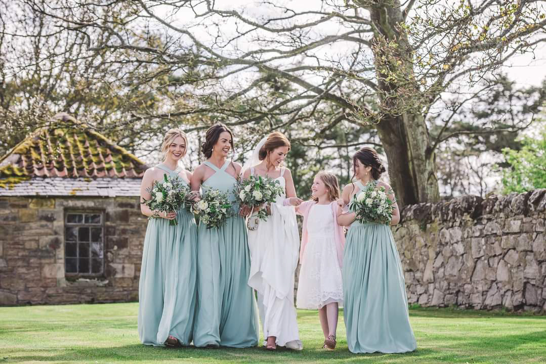 Bridal party with bouquets of white flowers, thistles and foliage