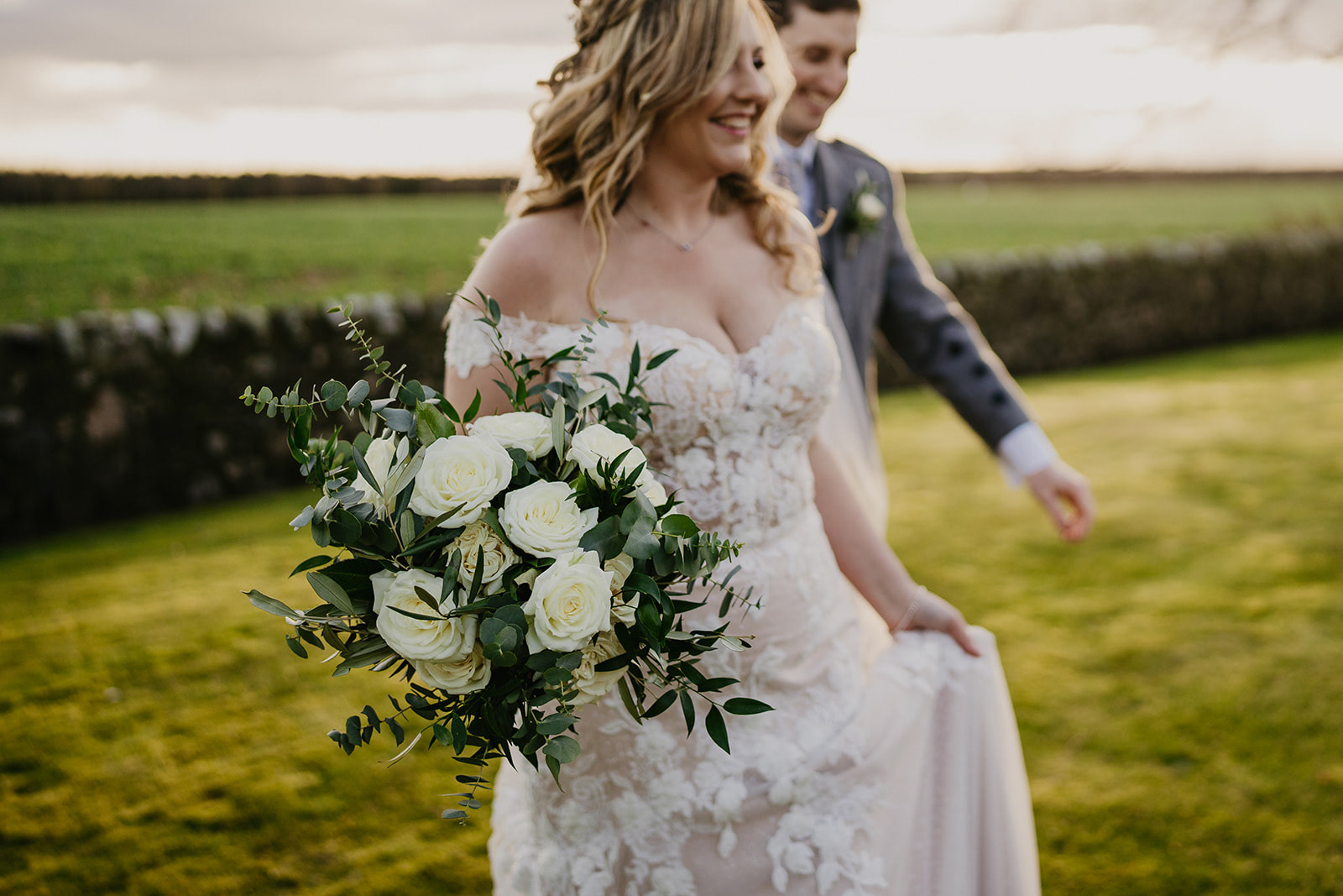 Bride carrying white rose and foliage bouquet