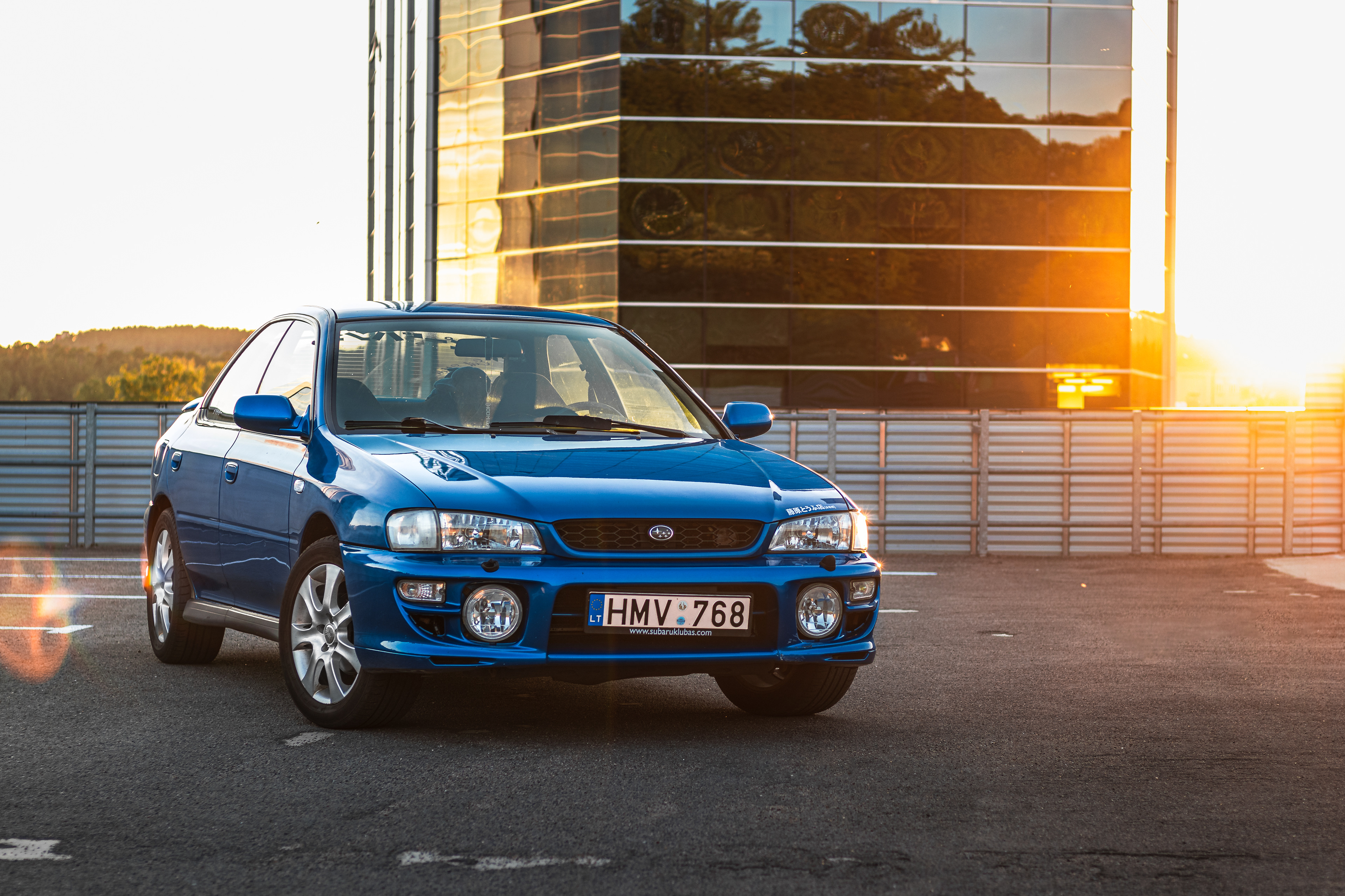 A Blue Subaru Impreza GC8 on a city roof during sunset