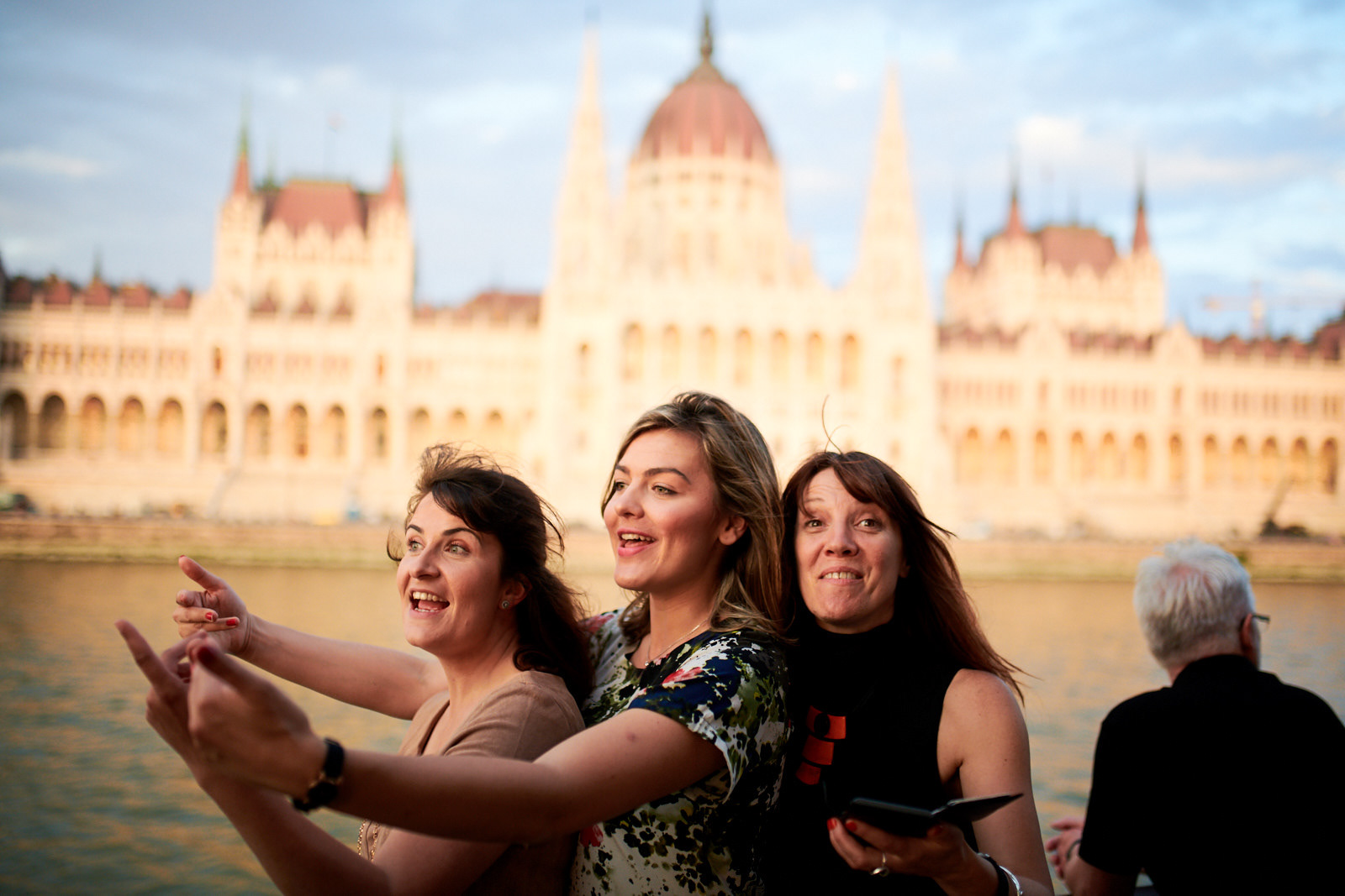 Happy attendees are posing at the boat party on the Danube, with the beautiful Parliament Building in the background.
