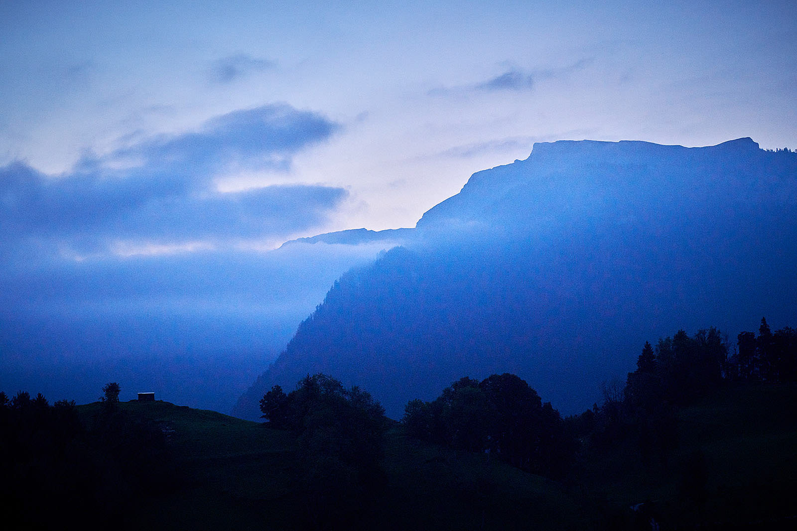 Swiss hills illuminated under the night sky.