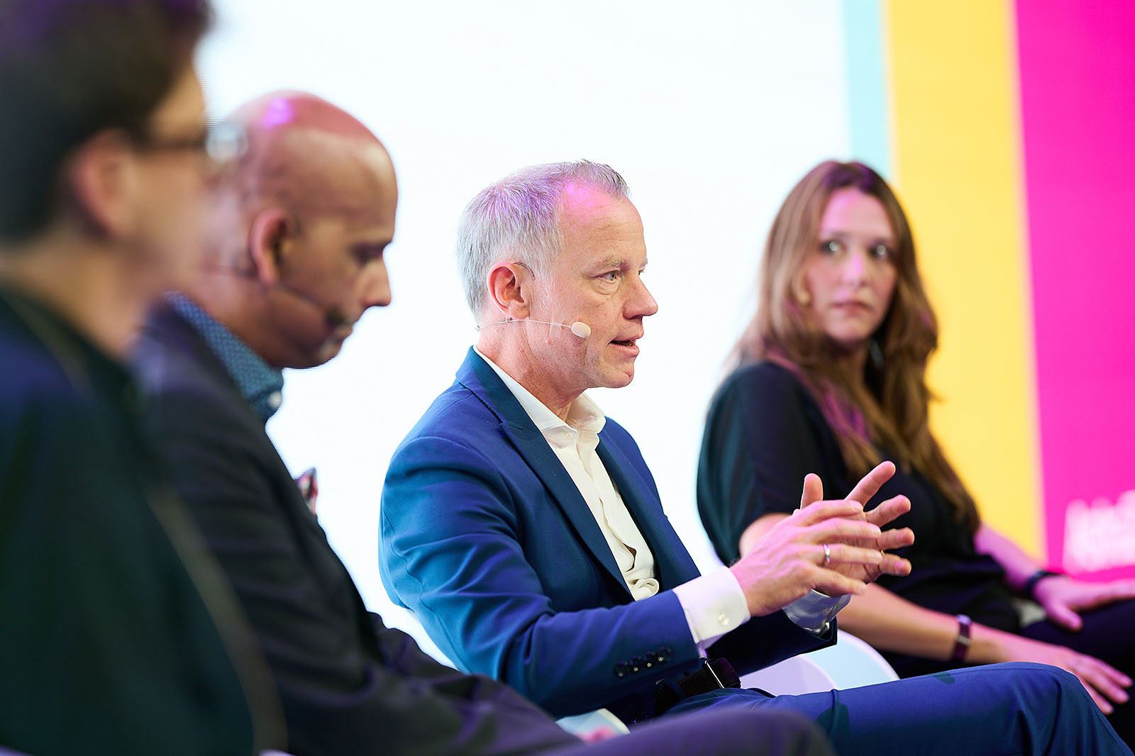 High-quality conference photography of corporate panel discussion on stage.