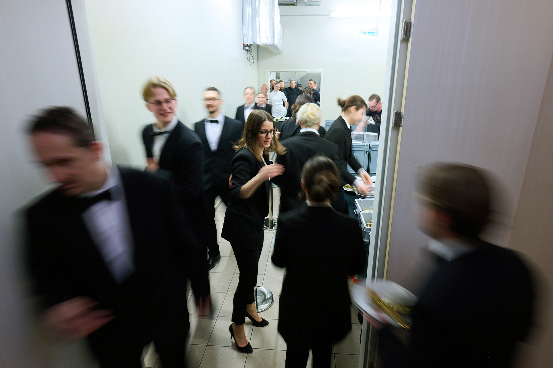 Dynamic shot of catering staff serving dinner to hundreds of guests at a gala reception