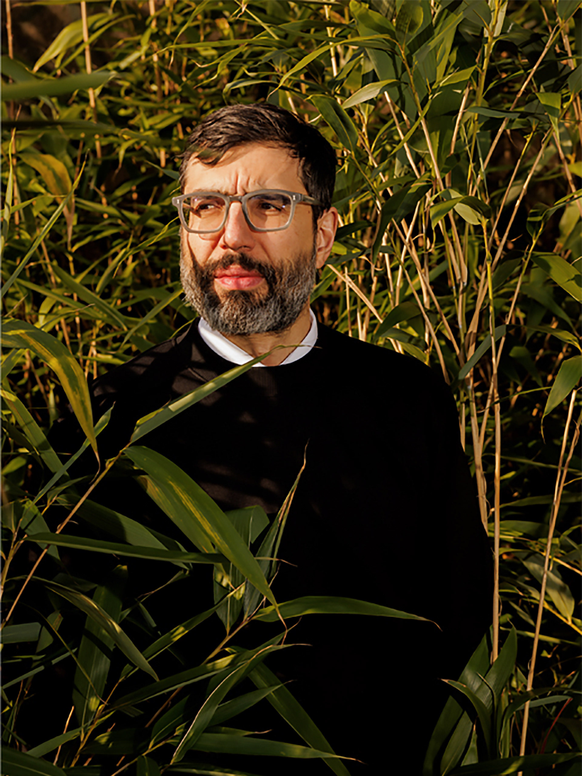 Portrait of Fine Artist David Cuesta standing in bamboo garden,looking to the side taken by Portrait Photographer Manuel Vazquez.