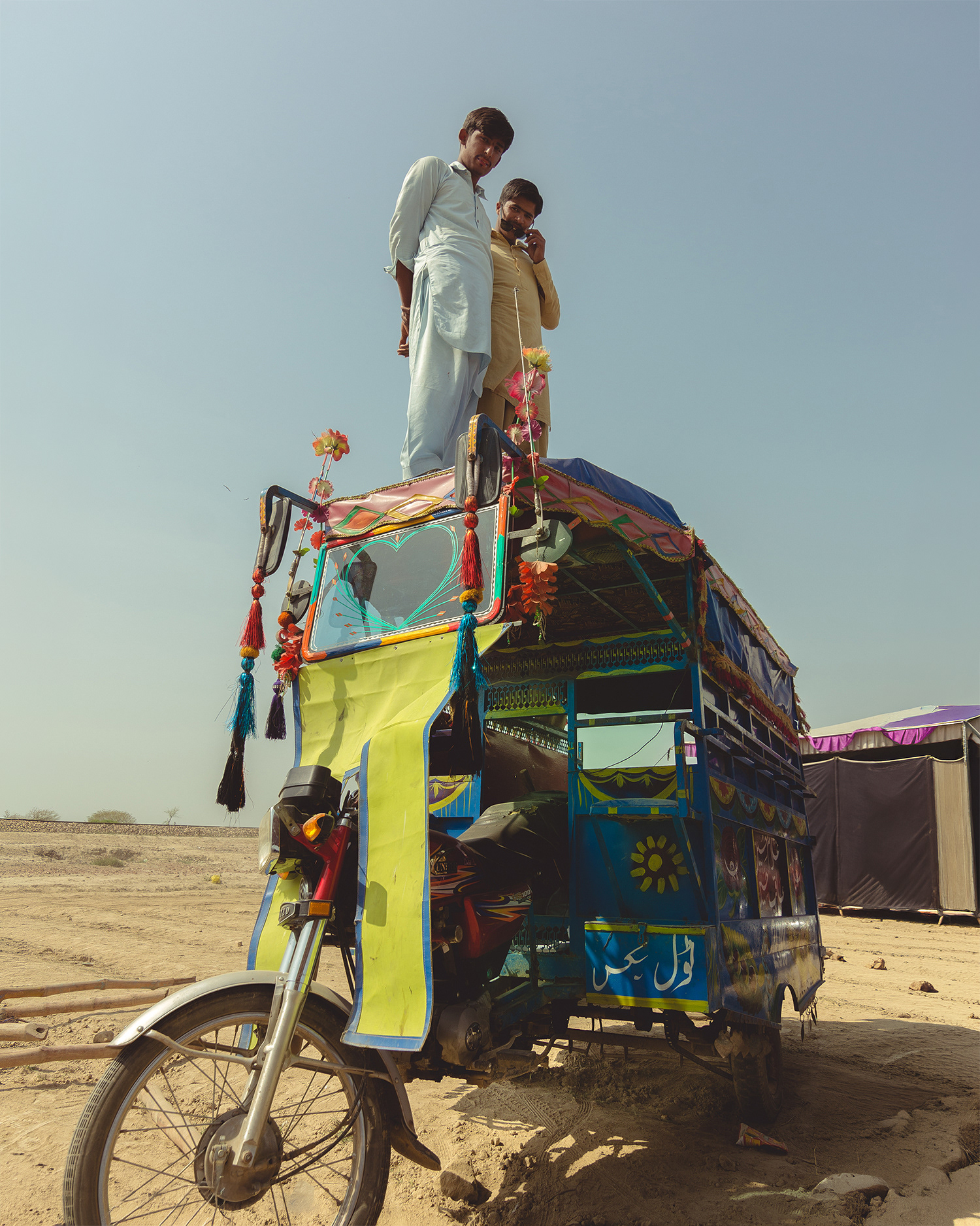Two guys standing on the chingchi rikshaw