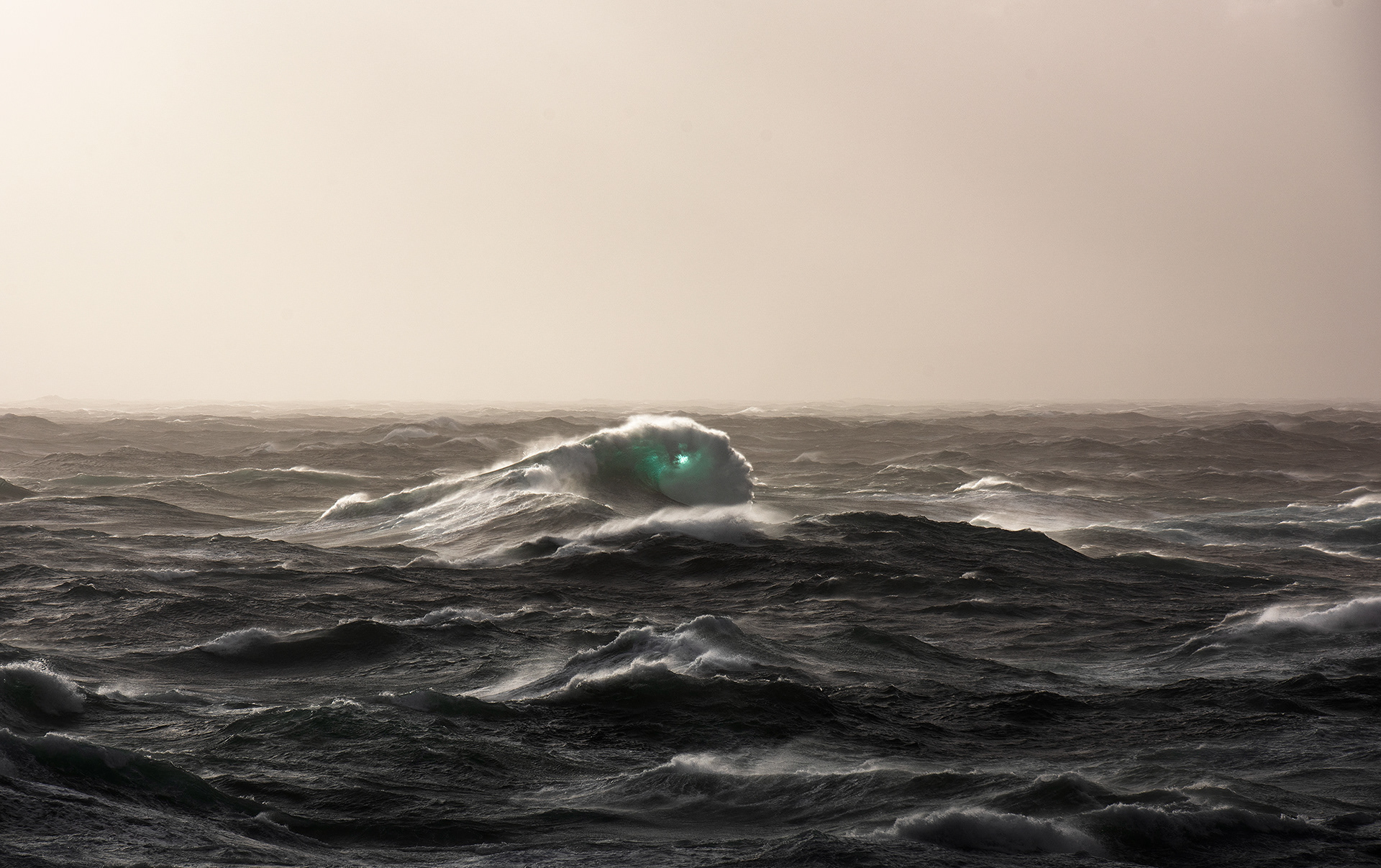 Backlight illuminates the barrel of an unscalable wave during a wild winter storm