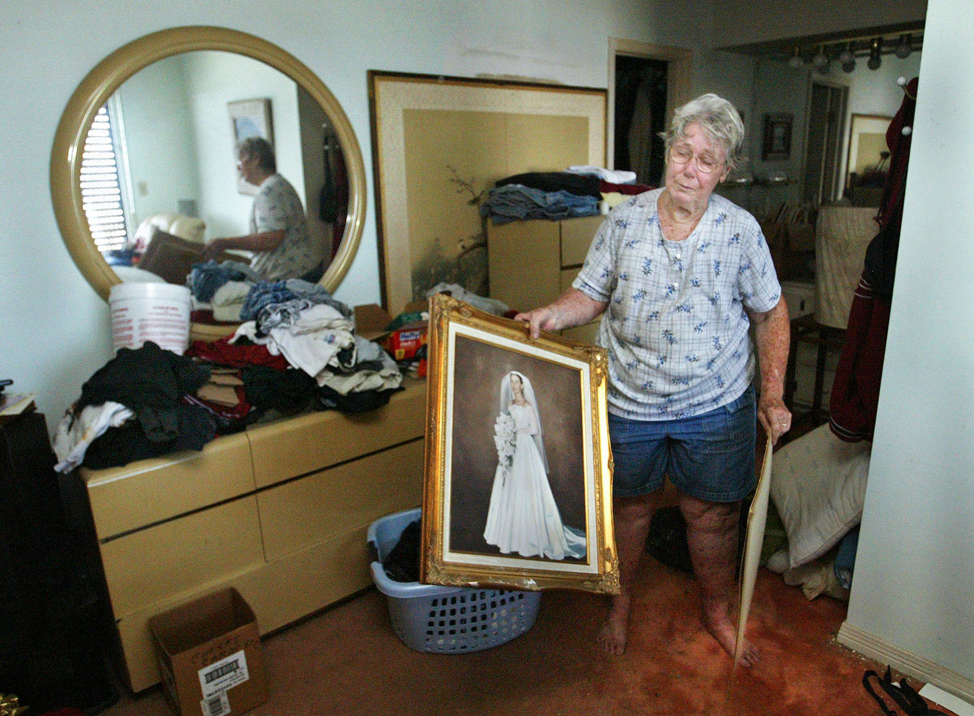Judy Curtis salvages her 1957 wedding photo in her damaged home from Hurricane Ivan.