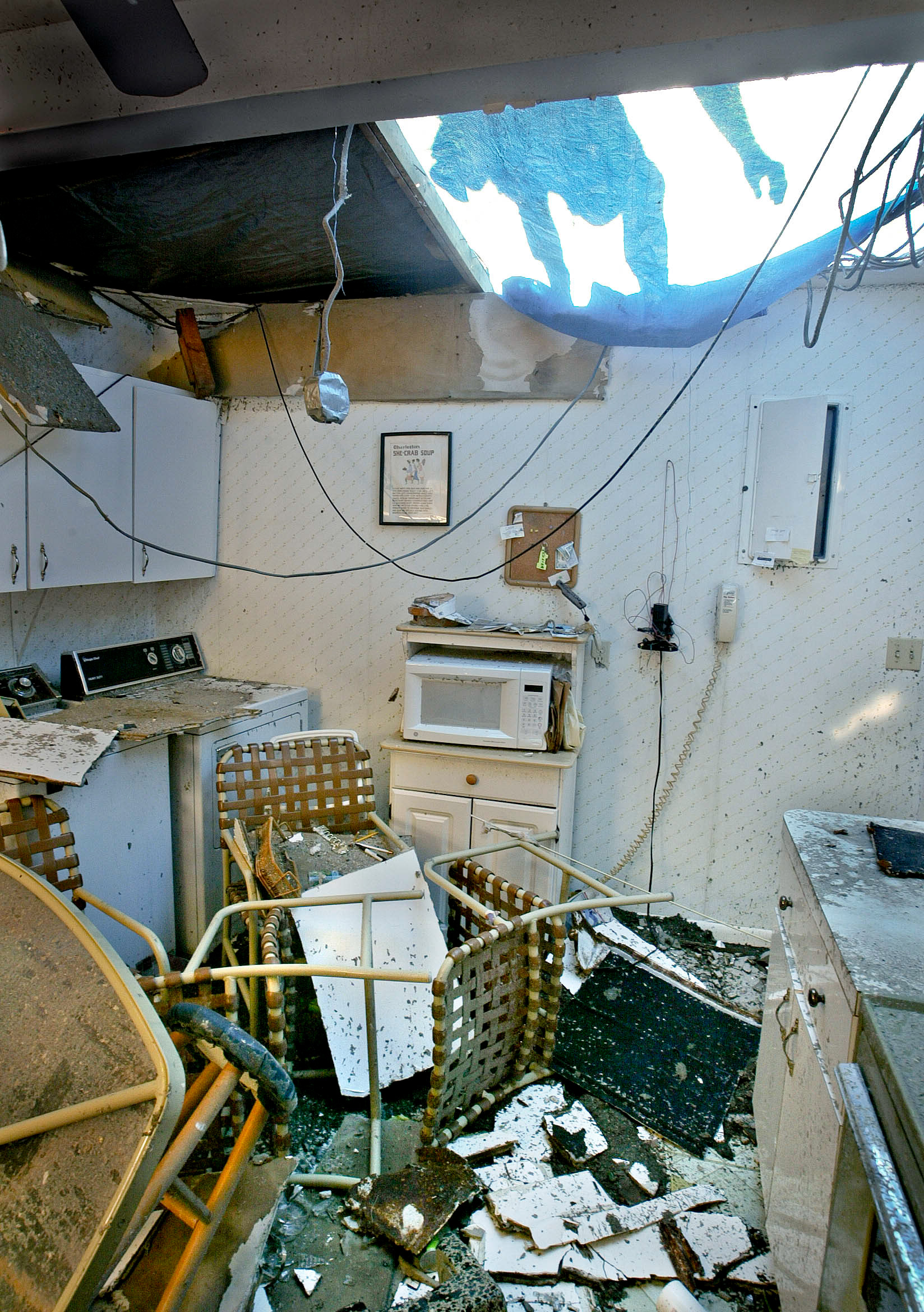 John Cain covers roof with tarp in house which had roof torn off by Hurricane Charlie.