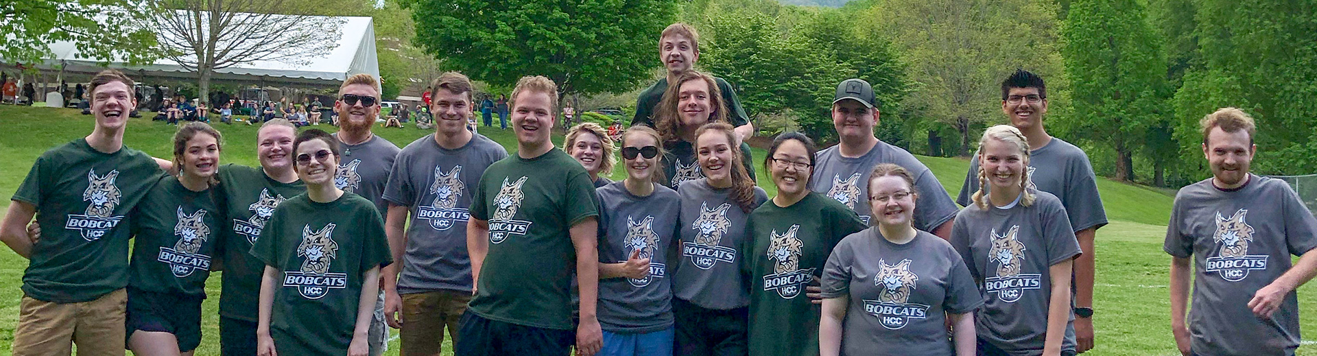 Group of students at event wearing shirts with new design in grey and school's green.