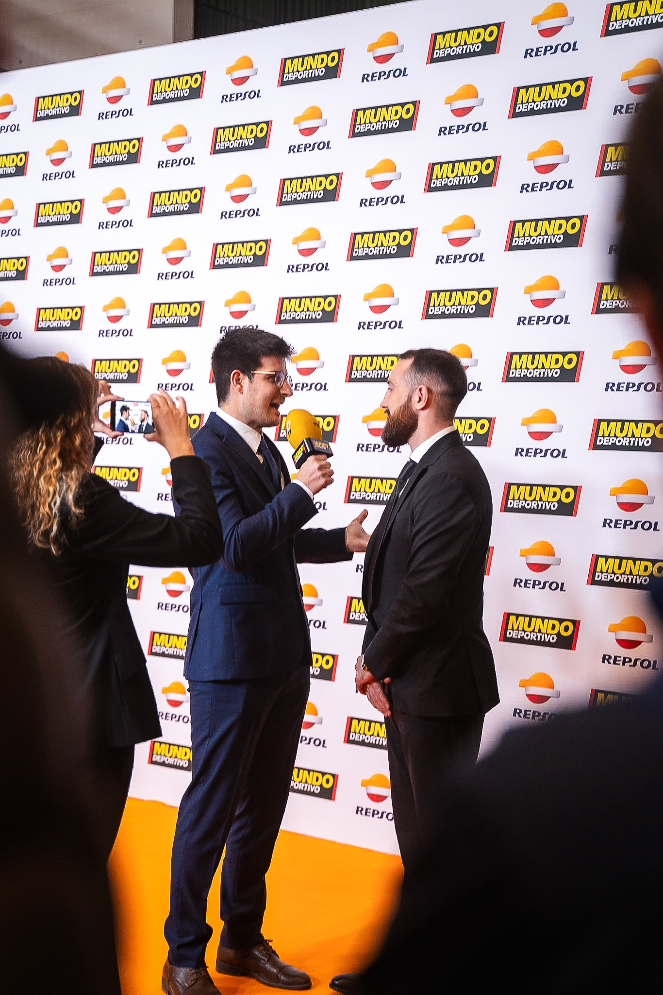 VIP guest arrivals photographed at gala event in Barcelona with step-and-repeat backdrop and controlled flash lighting